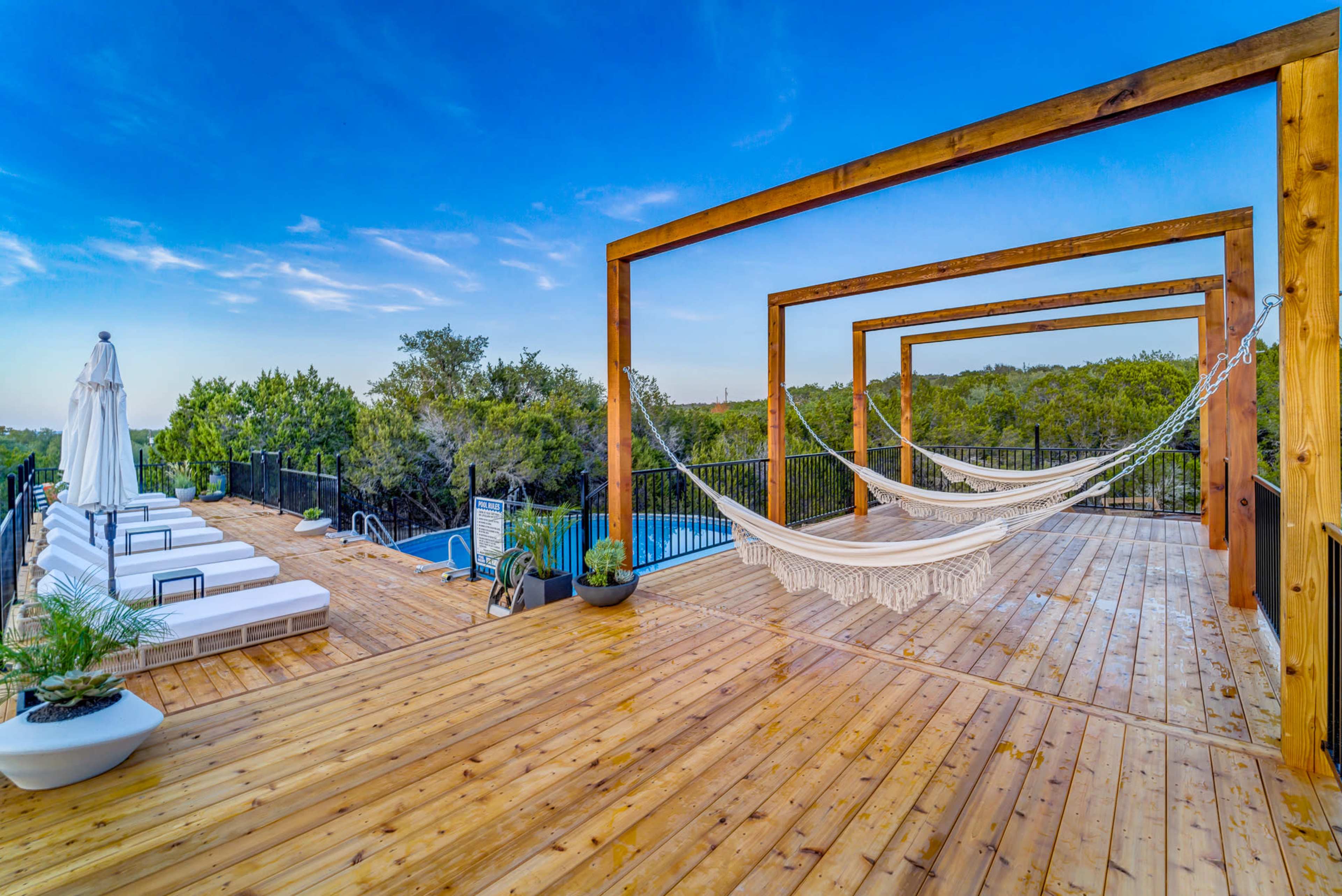 The image shows a wooden deck area featuring two hammocks, several lounge chairs, and a swimming pool surrounded by trees.