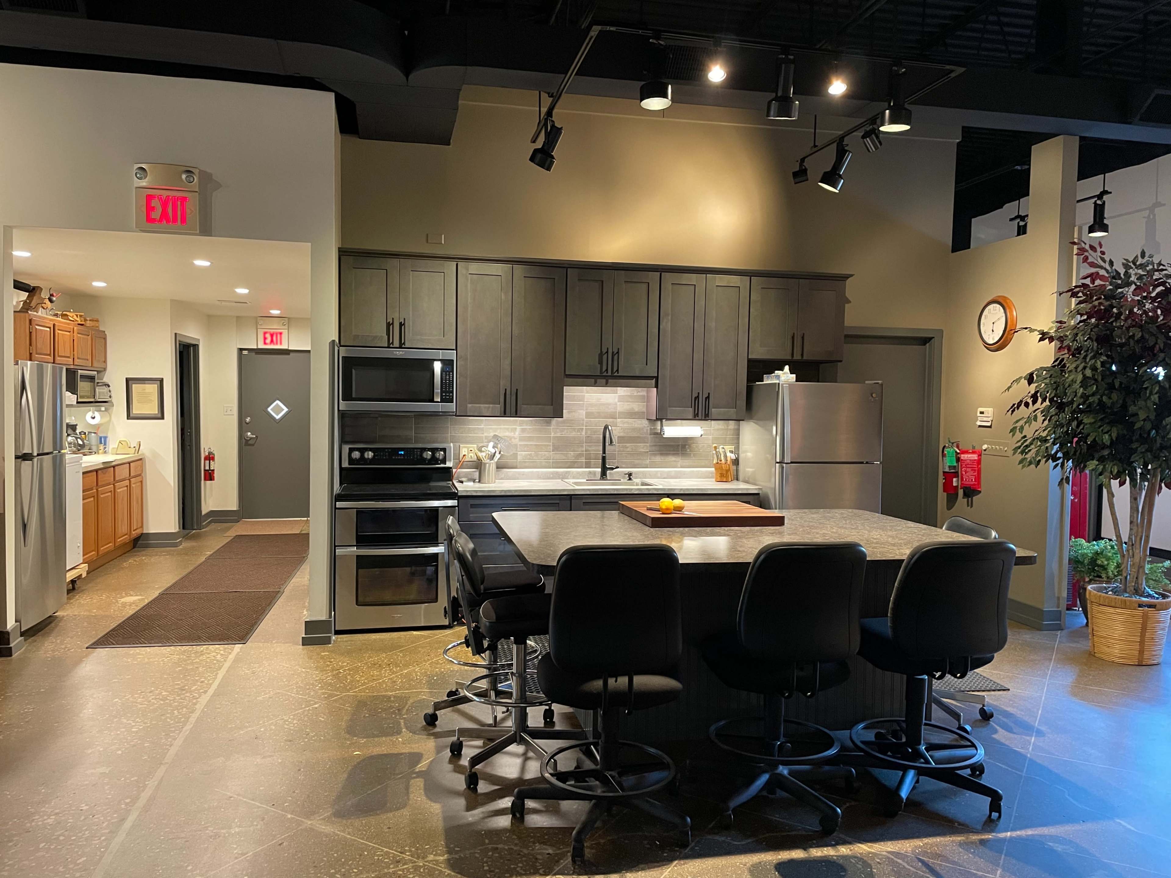 A modern kitchen with dark cabinetry, stainless steel appliances, and a large island with bar stools.