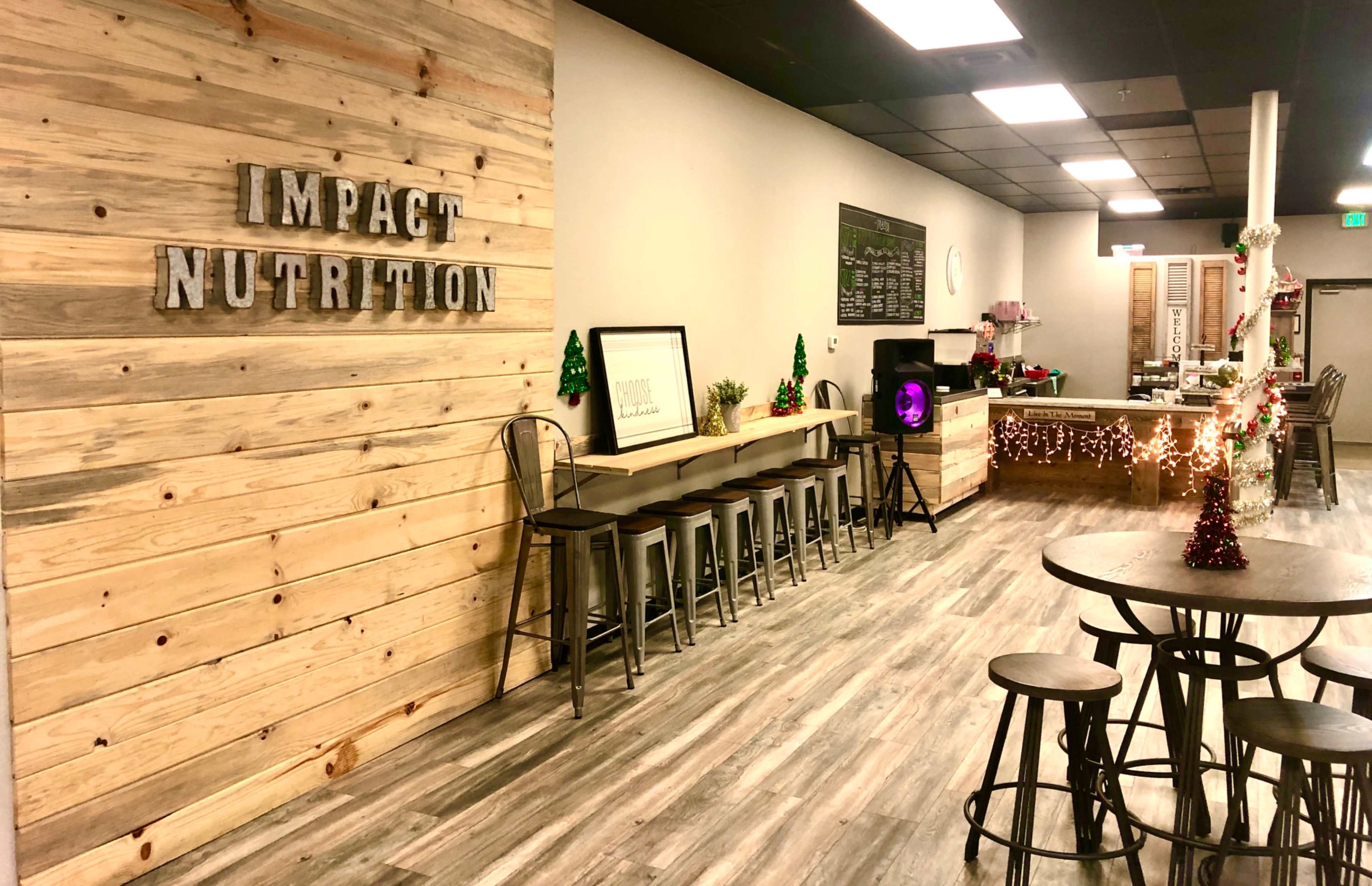 A modern nutrition shop with wooden walls, a counter with seating, and festive decorations.