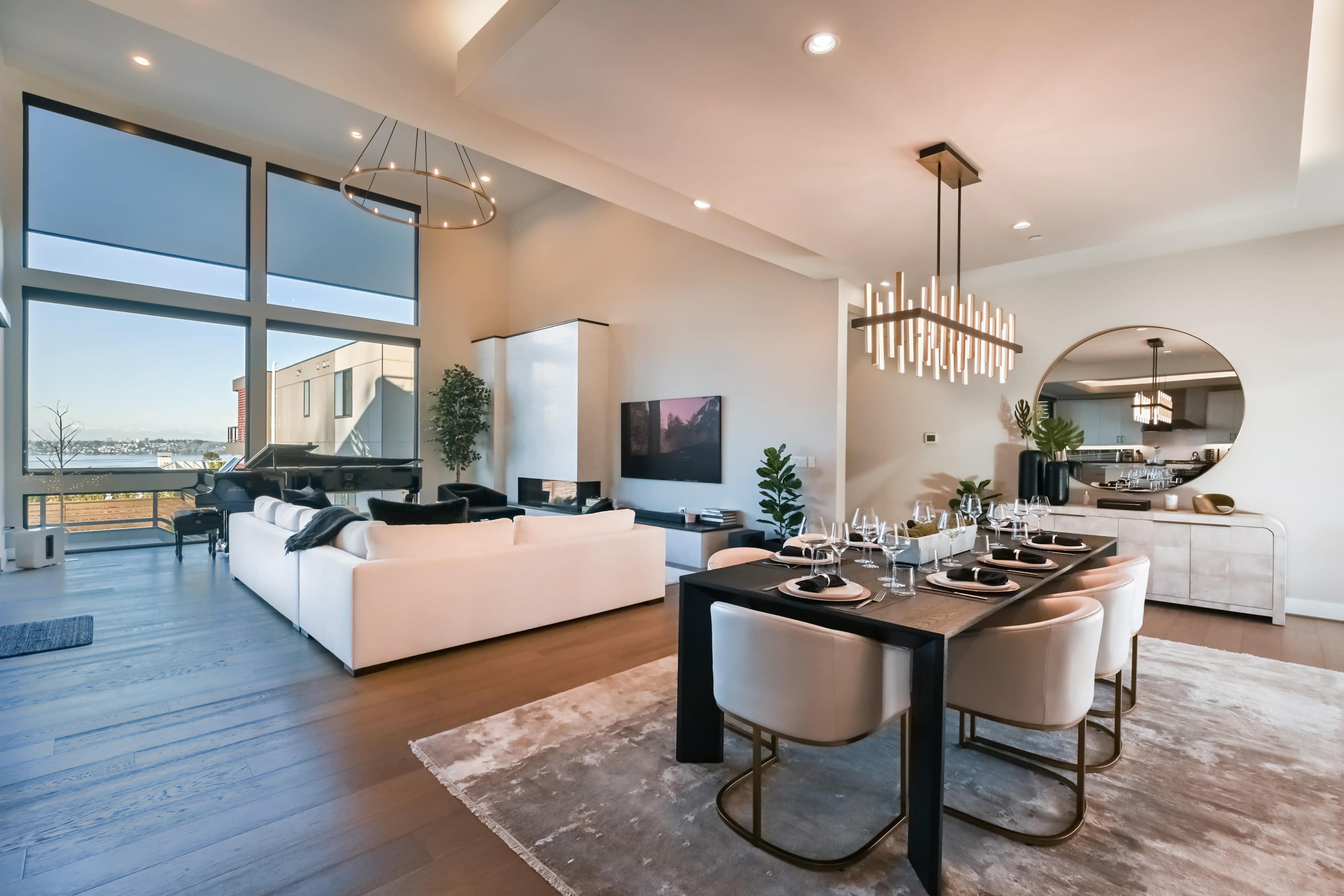 A modern interior featuring a spacious living and dining area with large windows, a white sofa, a black dining table, and contemporary decor elements.