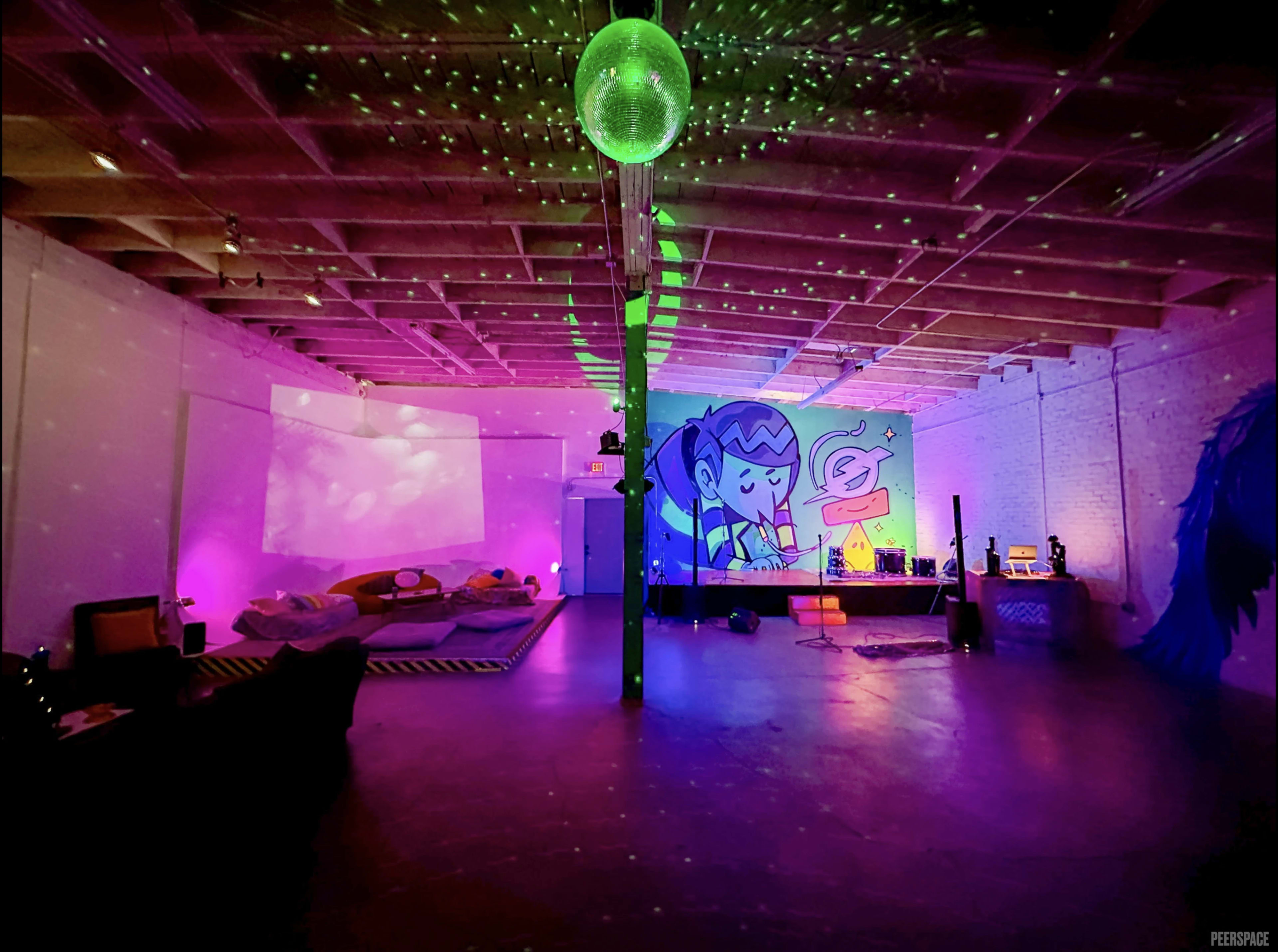 The image shows a colorful indoor space with a disco ball, vibrant lighting, and a mural on the wall, featuring a cartoon character.