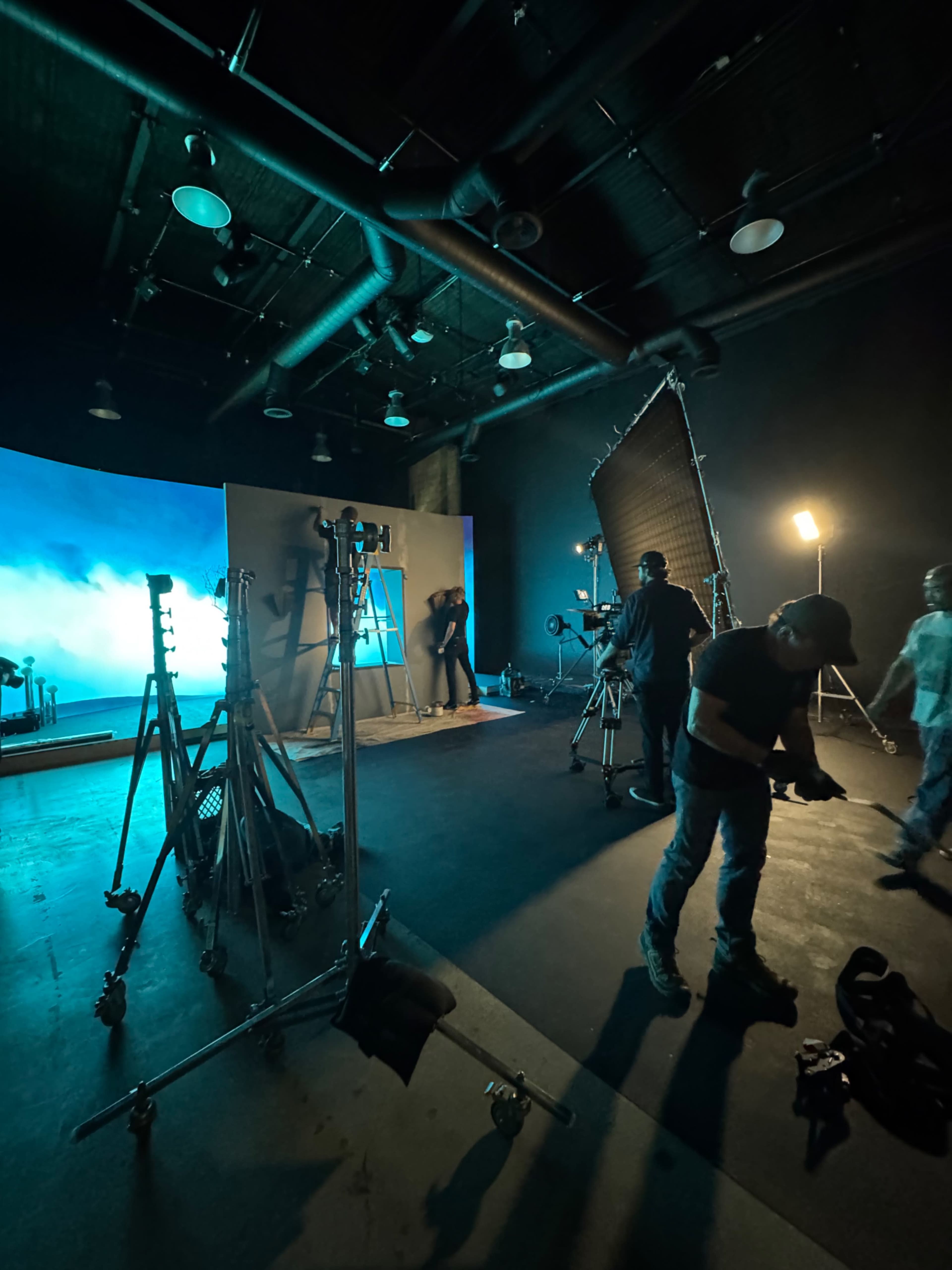 A film studio is set up with various lighting equipment and crew members preparing for a shoot.