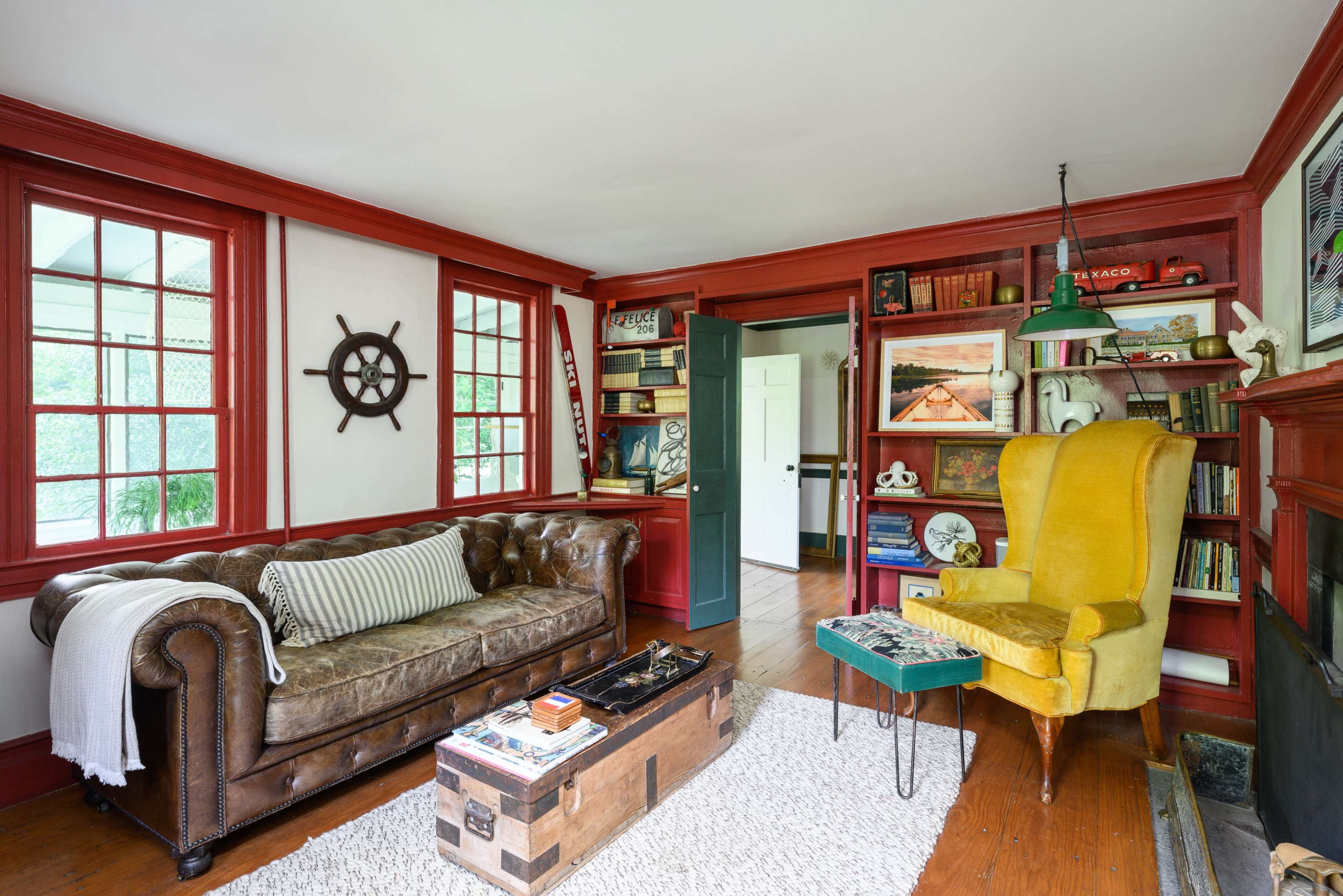 The image features a living room with a brown leather sofa, a yellow armchair, wooden flooring, and a bookshelf filled with books and decorative items.