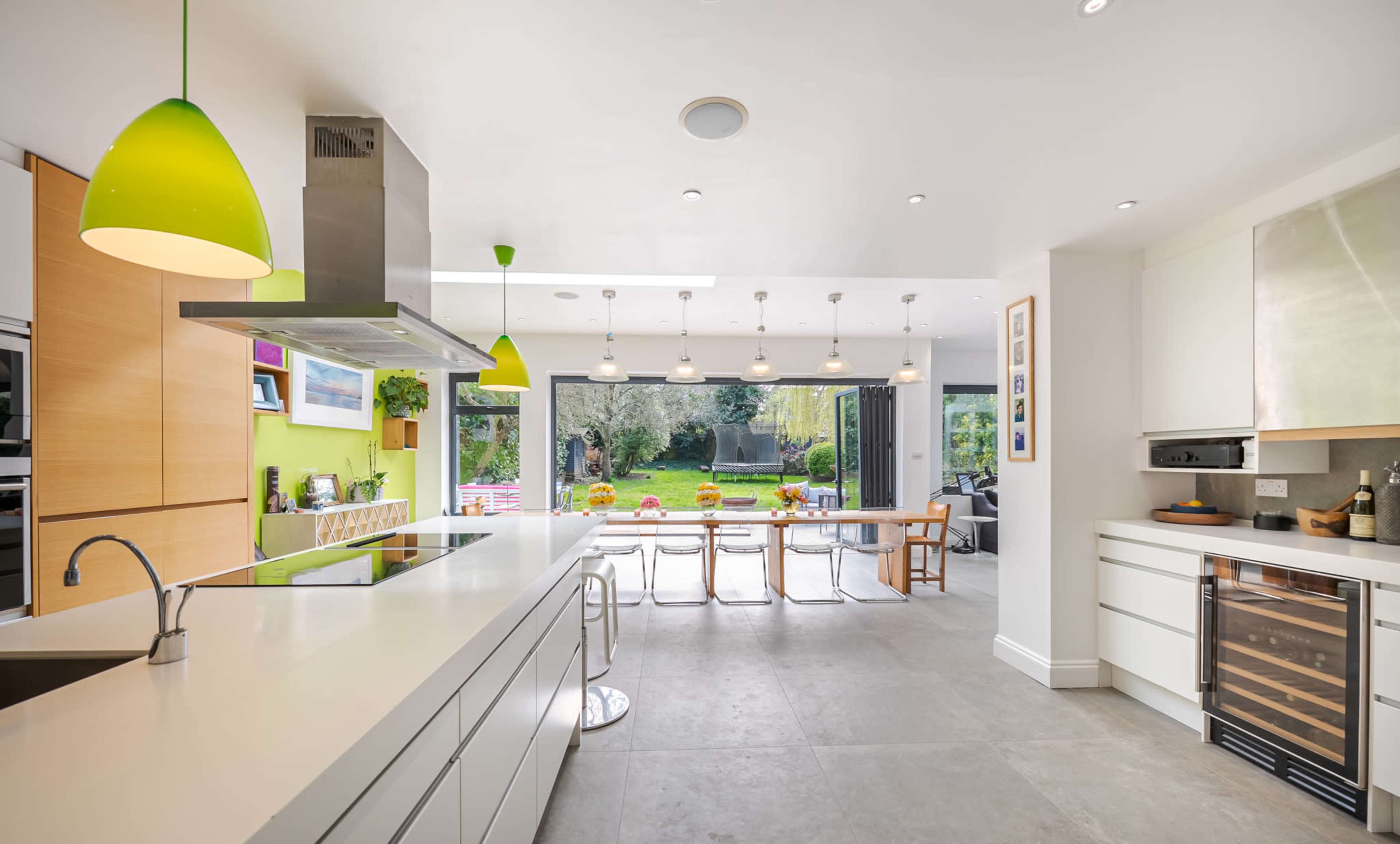 A modern kitchen opens up to a stylish dining area with large glass doors leading to a garden.
