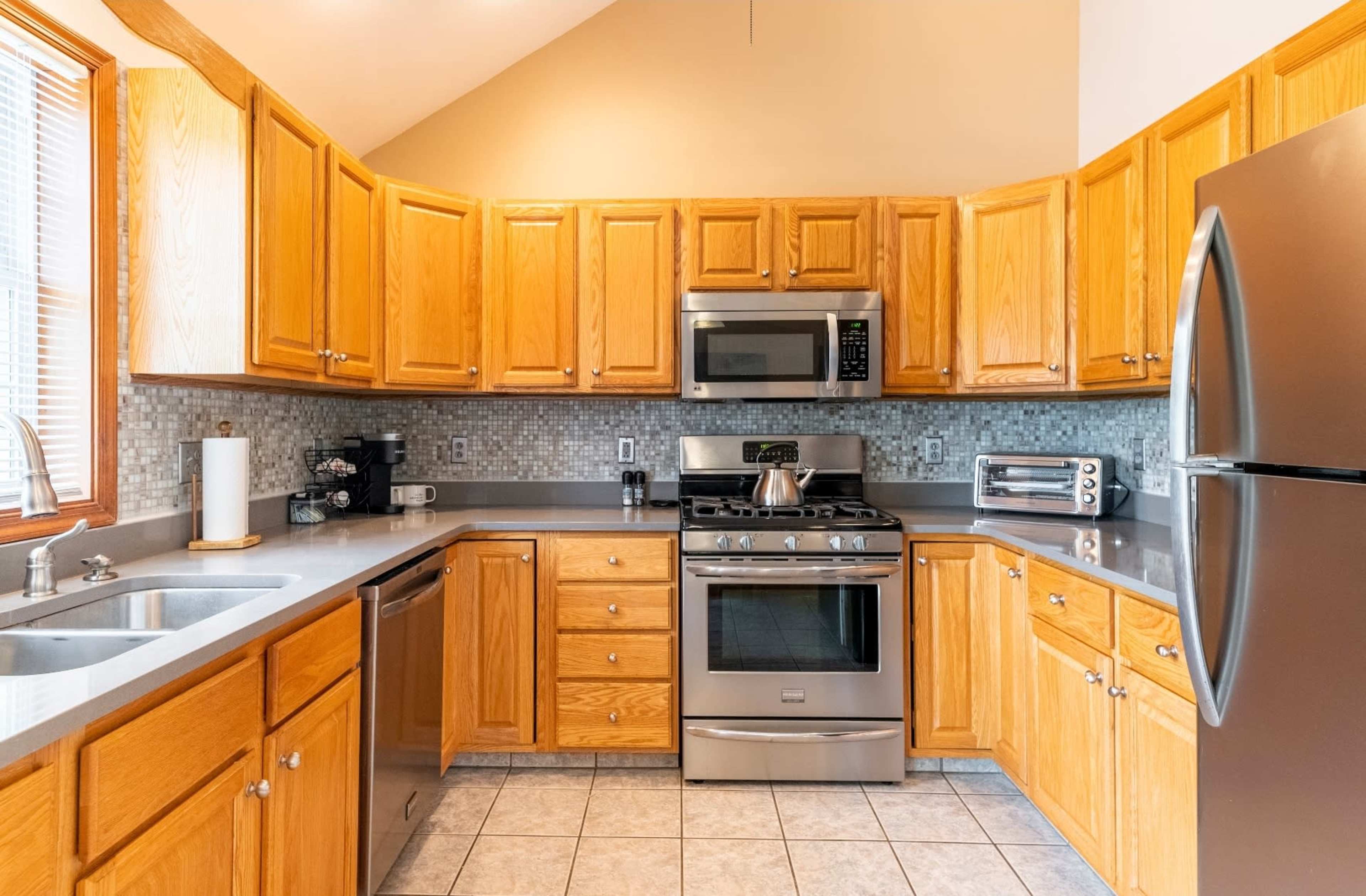 A kitchen with wooden cabinets, stainless steel appliances, and a gray countertop.