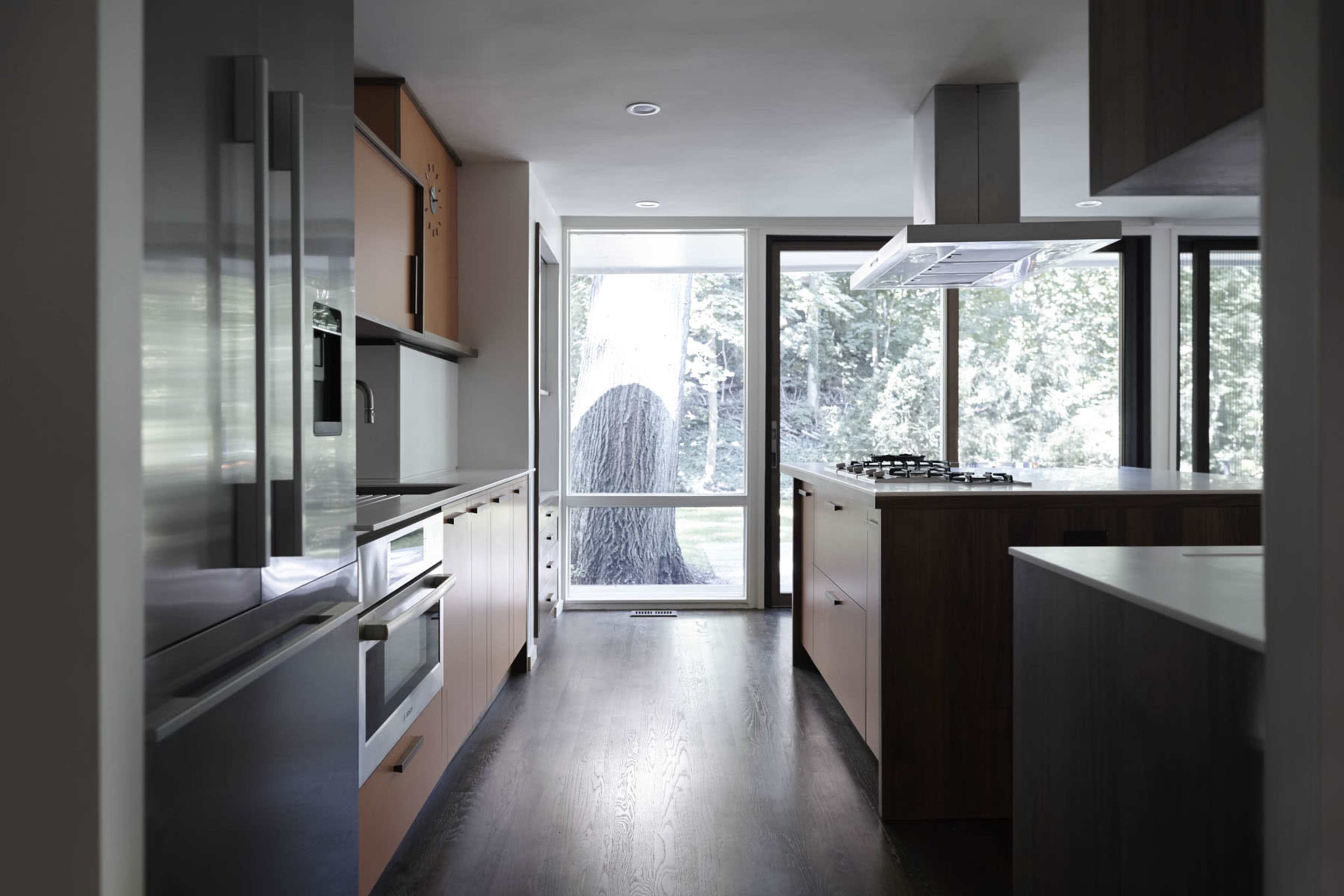 The kitchen features modern appliances and cabinetry with a large window that overlooks a tree-filled yard.