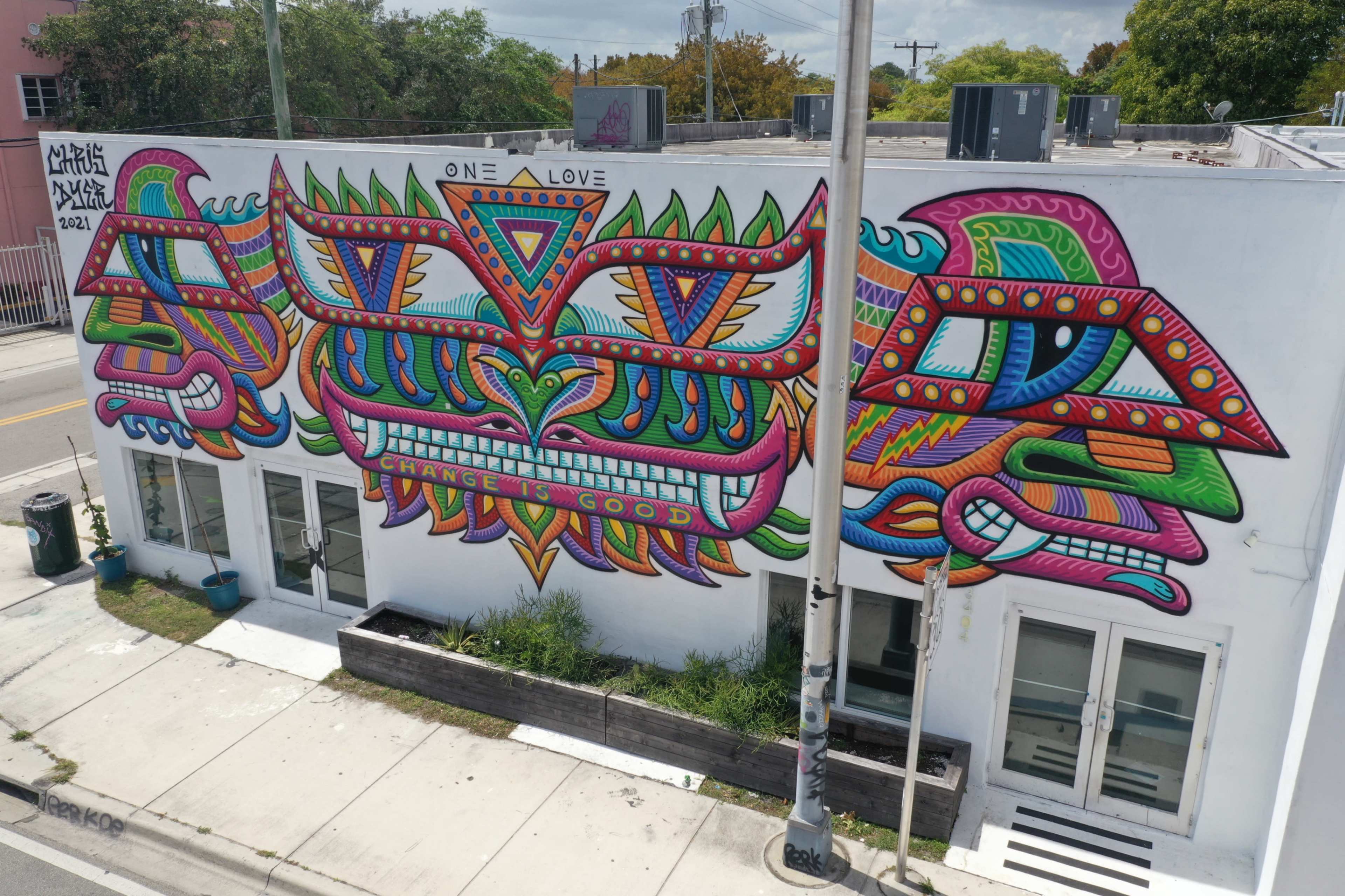 A colorful mural on the side of a building featuring abstract designs and the phrase "One Love" prominently displayed in the center.