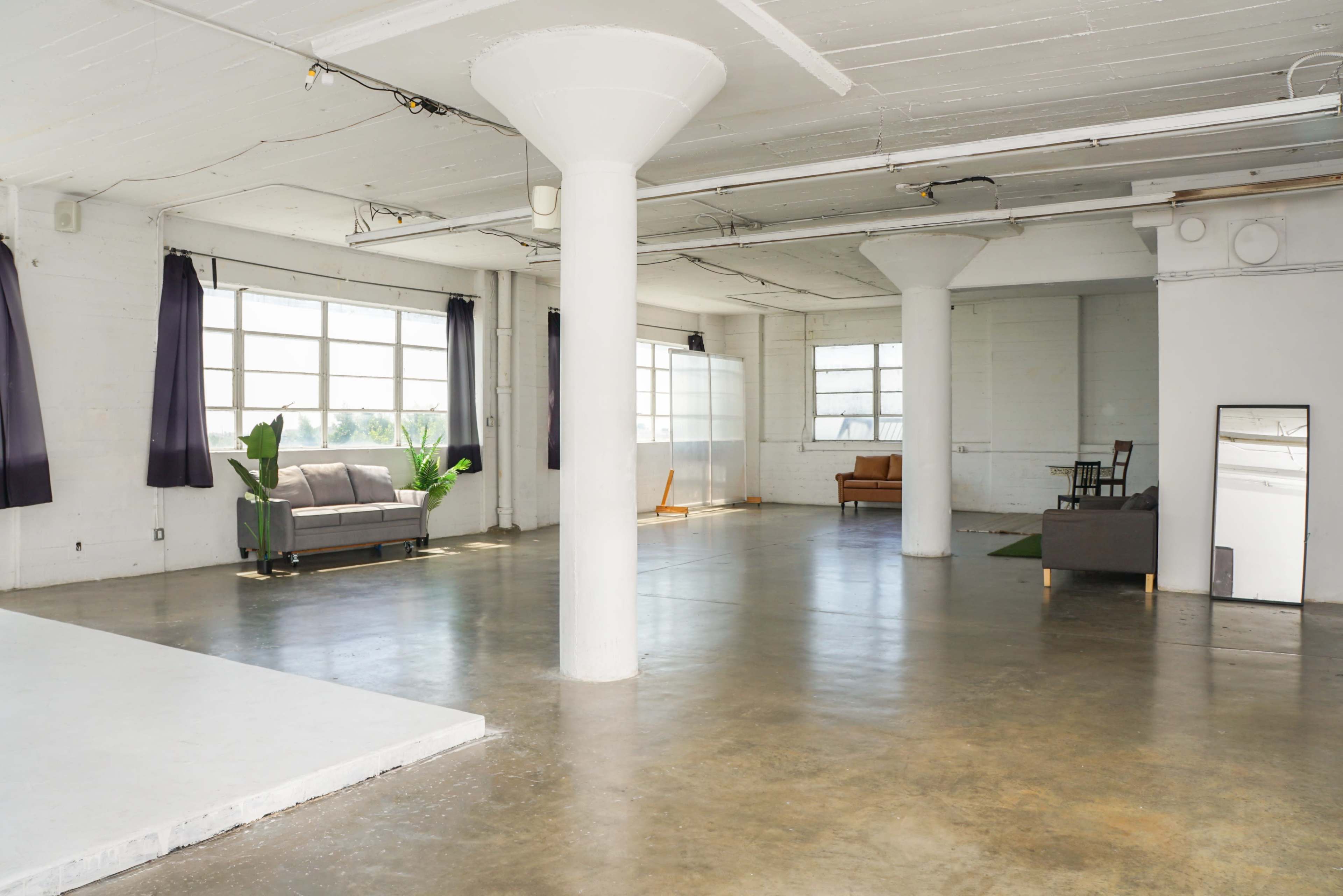 Blackout Loft Studio with central AC, a pre-lit corner cyc wall, Light Tunnel, wooden platform, white wooden reclaimed wall & frameless window with downtown view - PRO II Image in Central LA, Los Angeles, CA