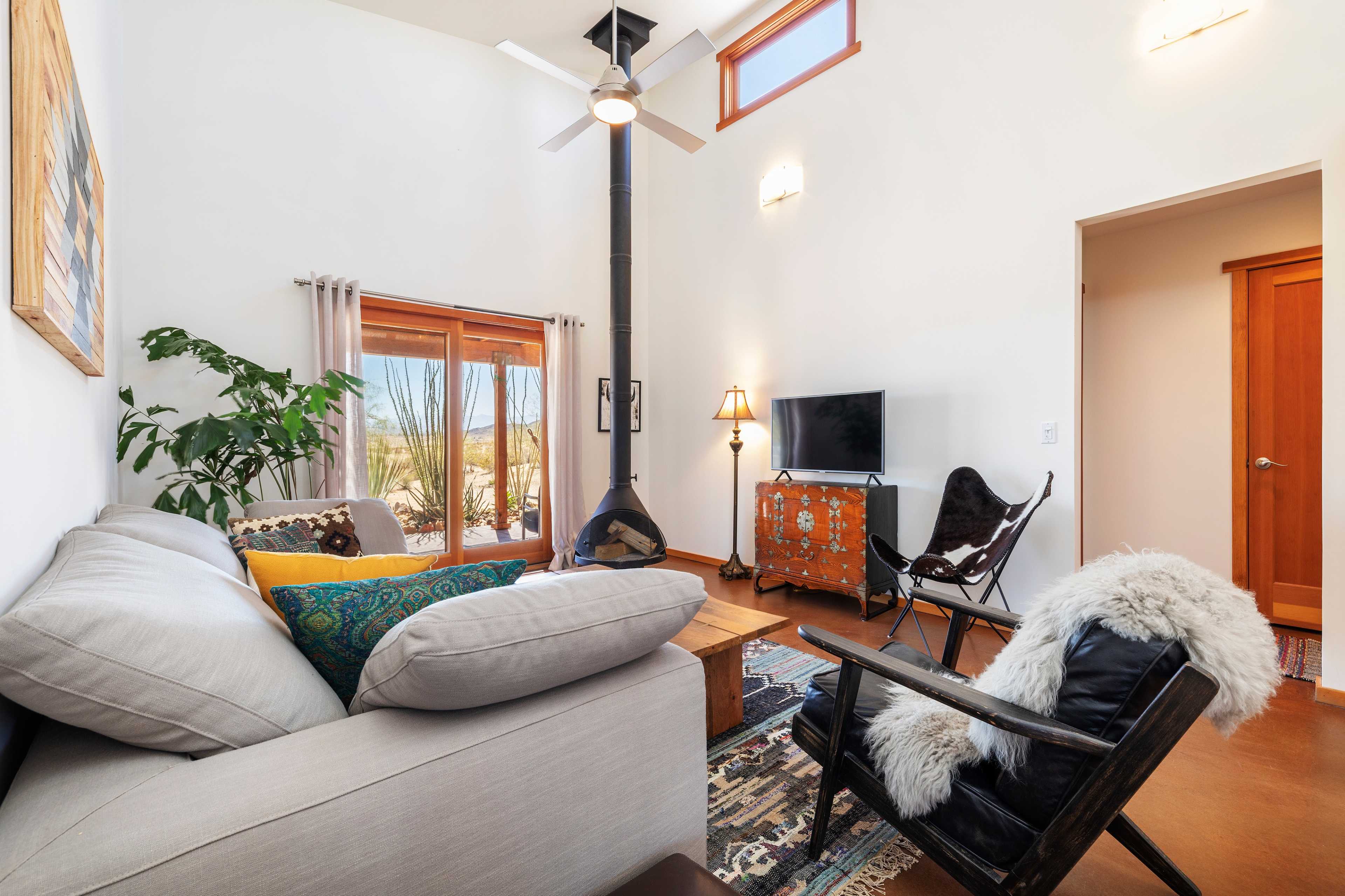 A cozy living room featuring a sofa, a unique wood stove, a television, and a mix of modern and rustic furnishings.