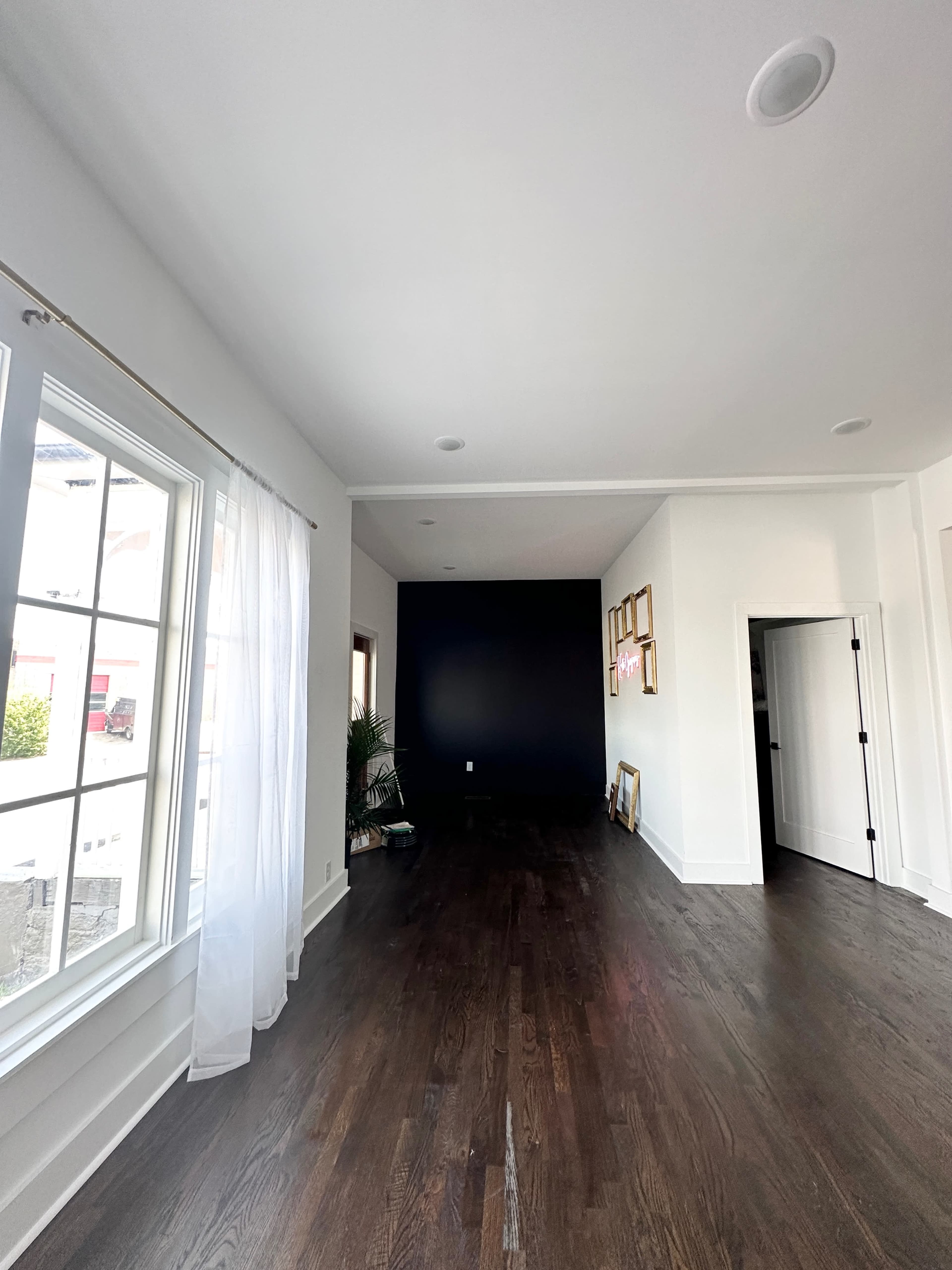 A spacious, well-lit room with dark wood flooring, white walls, and a contrasting dark blue accent wall.
