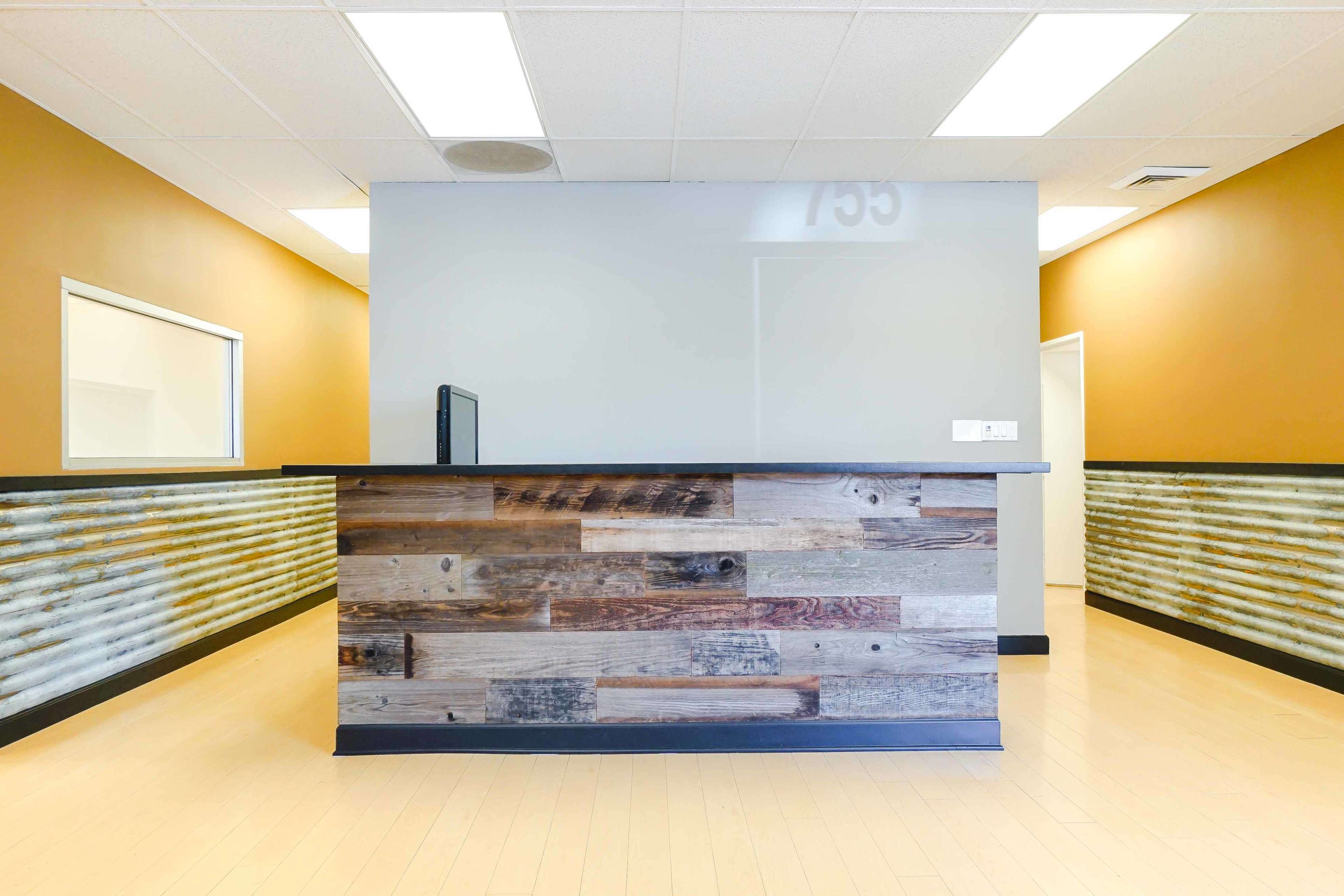 A reception area featuring a wooden front desk with a sleek design, set against a backdrop of orange and light gray walls.