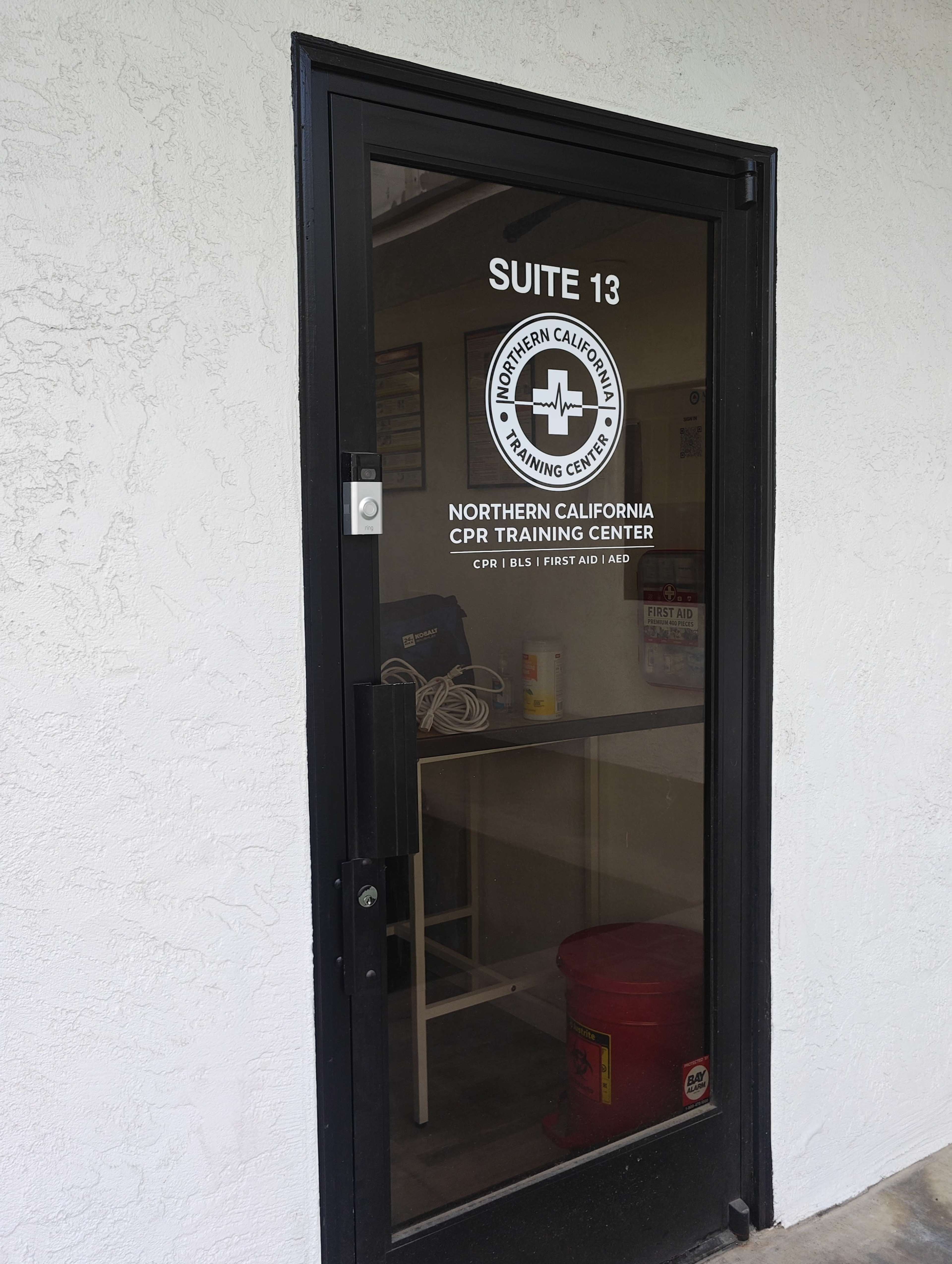 The image shows the entrance door of Suite 13, identified as the Northern California CPR Training Center, with a clear glass panel and signage.
