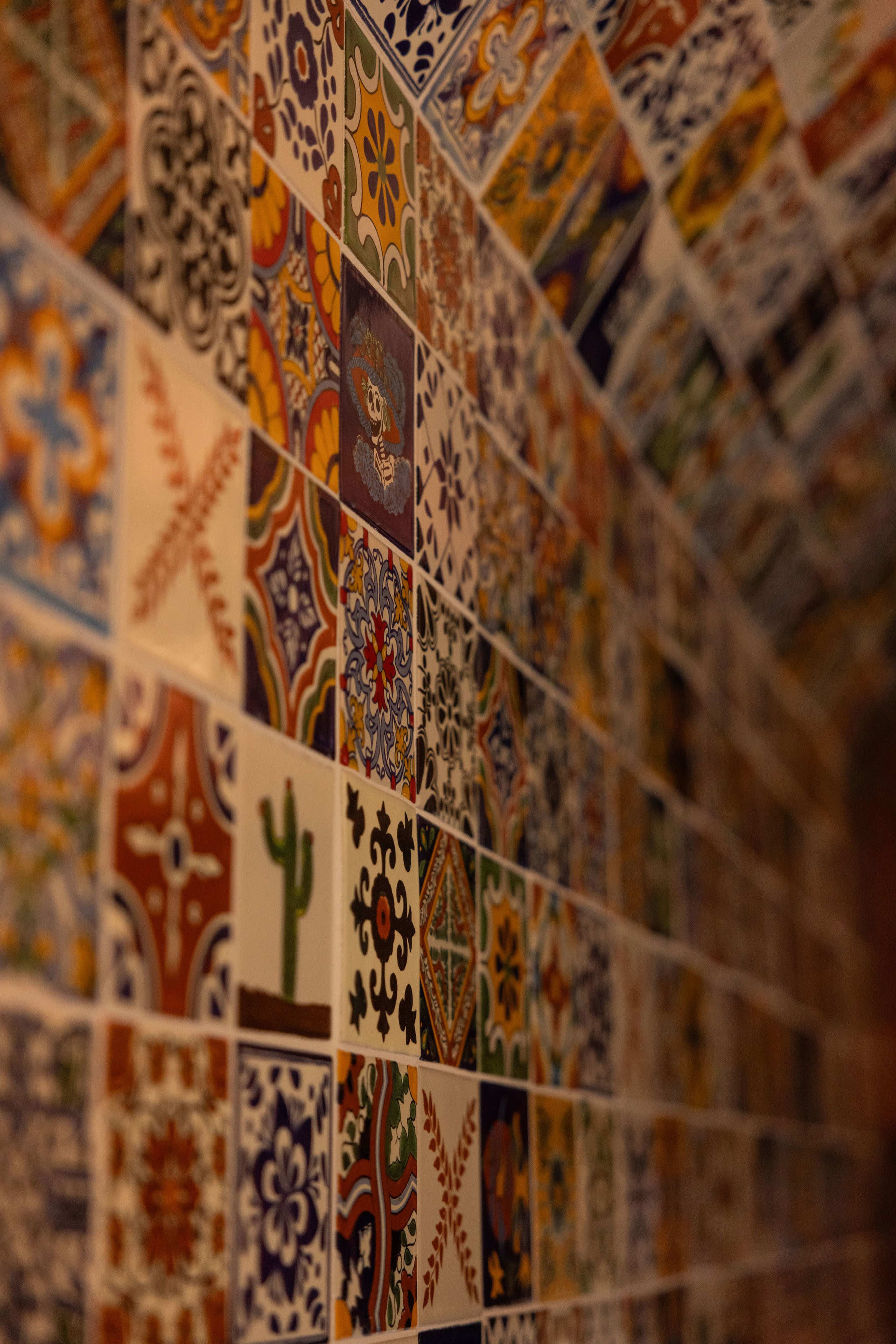 The image shows a vibrant mosaic of colorful, patterned tiles arranged in a wall.