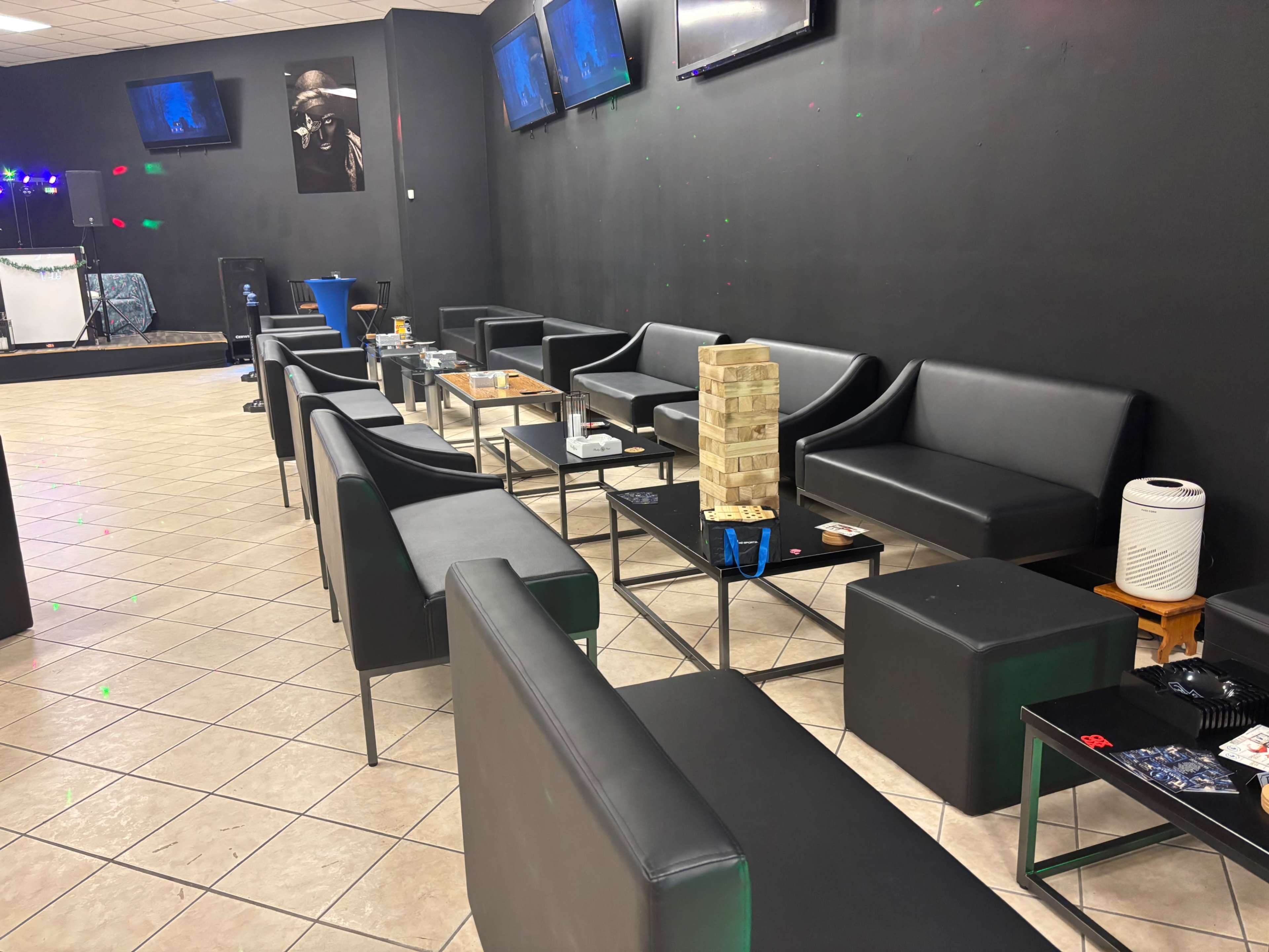 A lounge area features black leather seating and glass-topped tables, with a Jenga tower centered among the furniture.