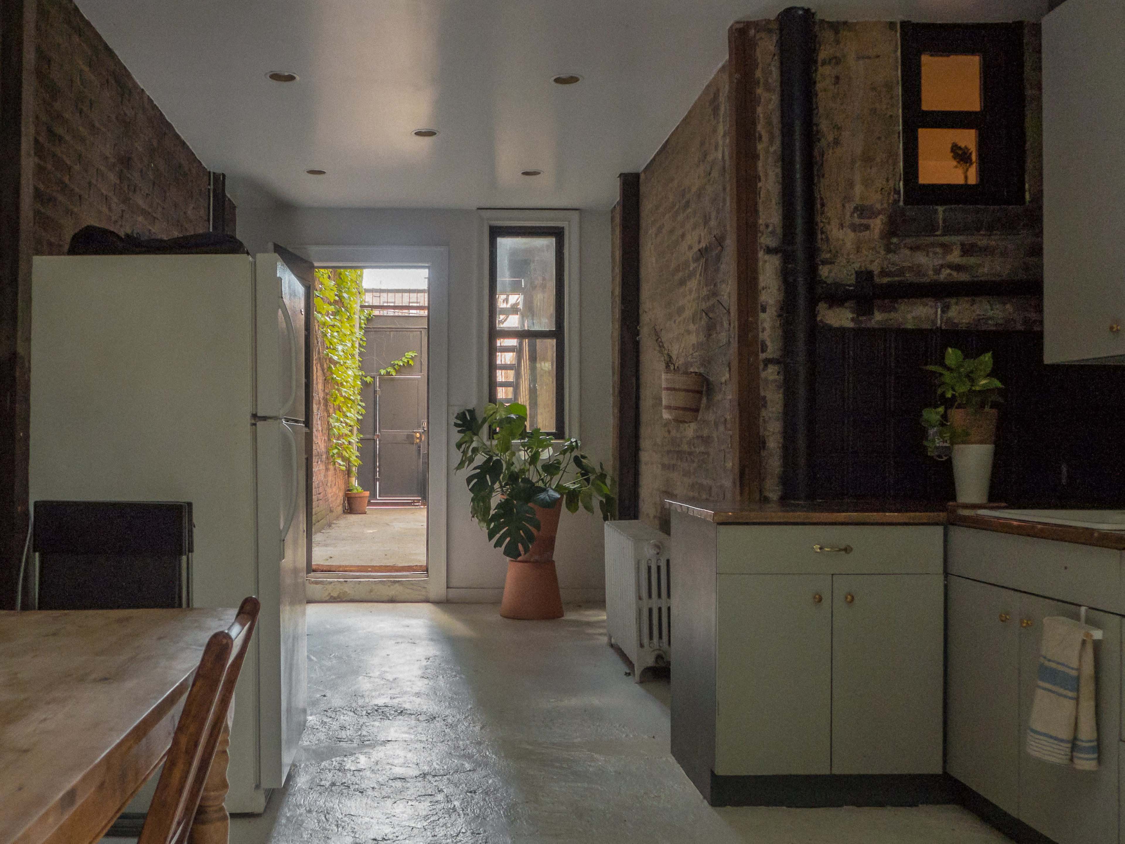 A spacious kitchen with a refrigerator, dining table, and a doorway leading to a backyard area.