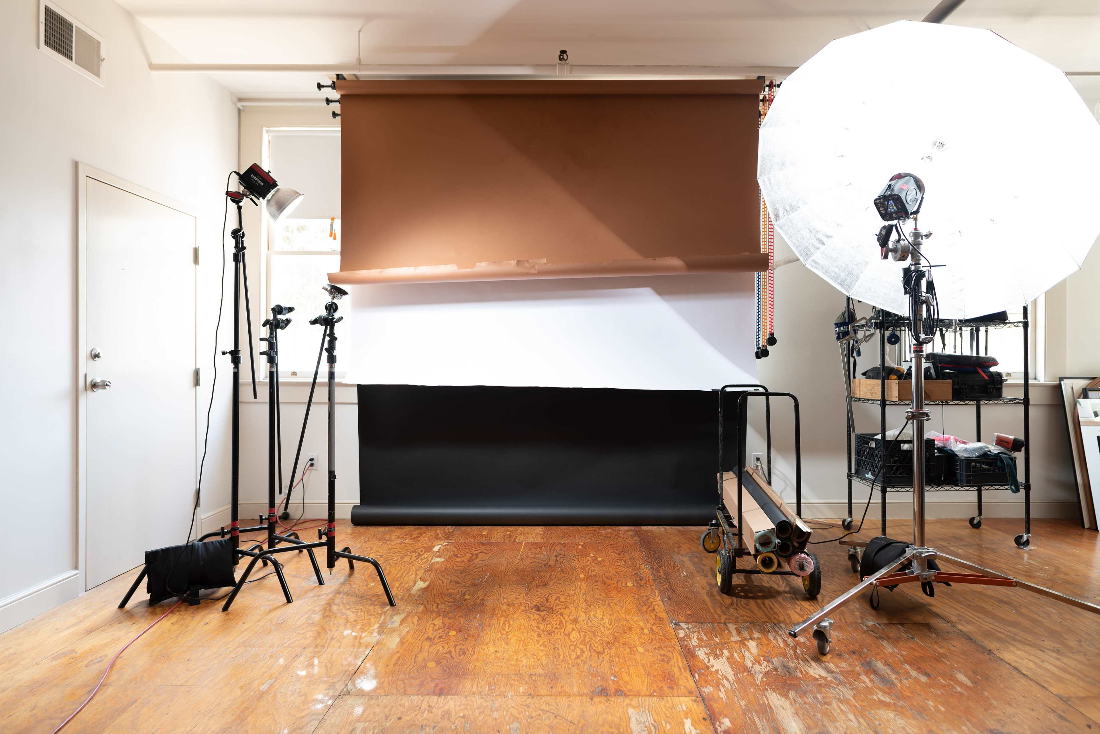 A photography studio features a backdrop of brown and black paper along with lighting equipment on stands.