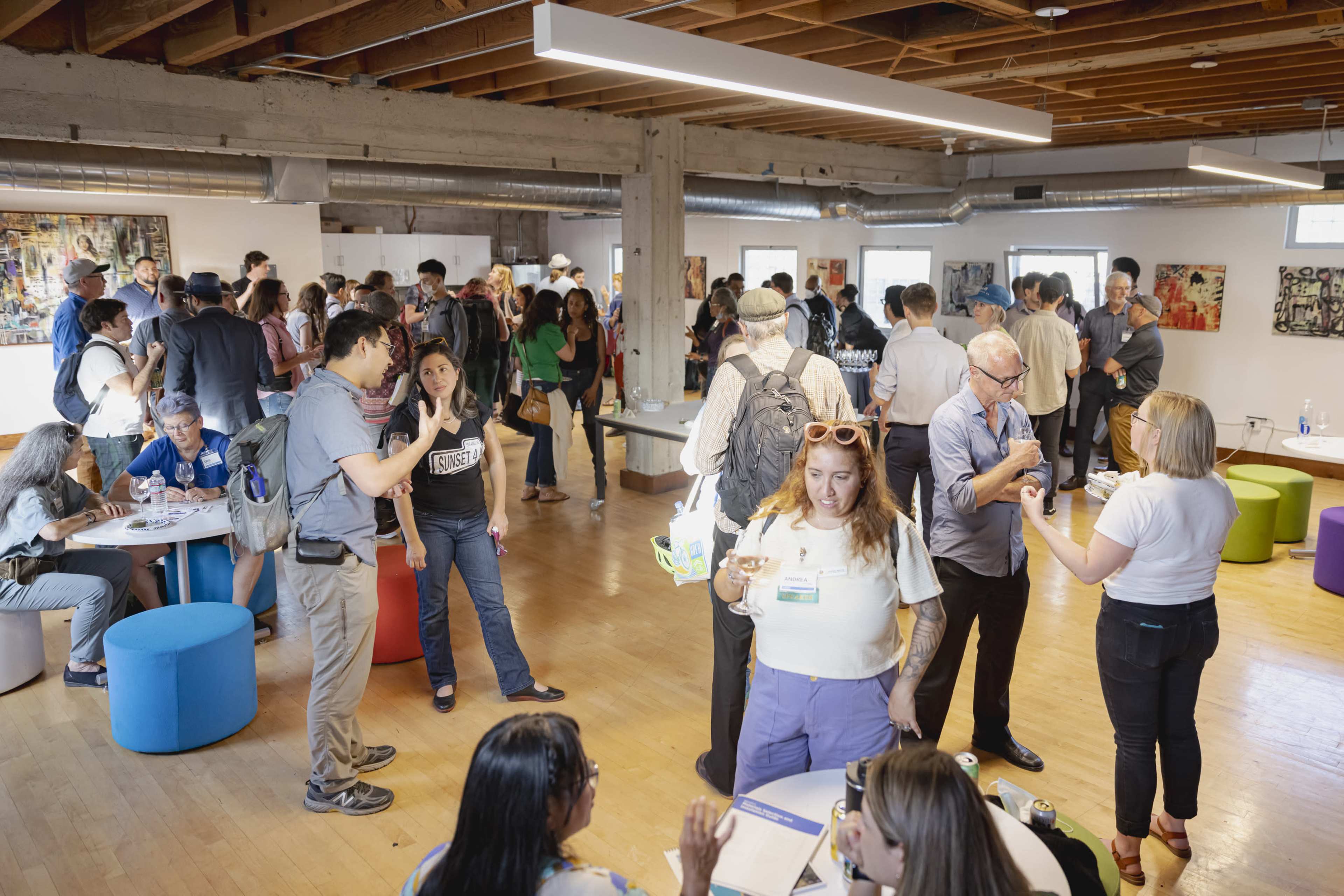 A group of people is gathered in a spacious, well-lit room with modern decor, engaging in conversation and networking.
