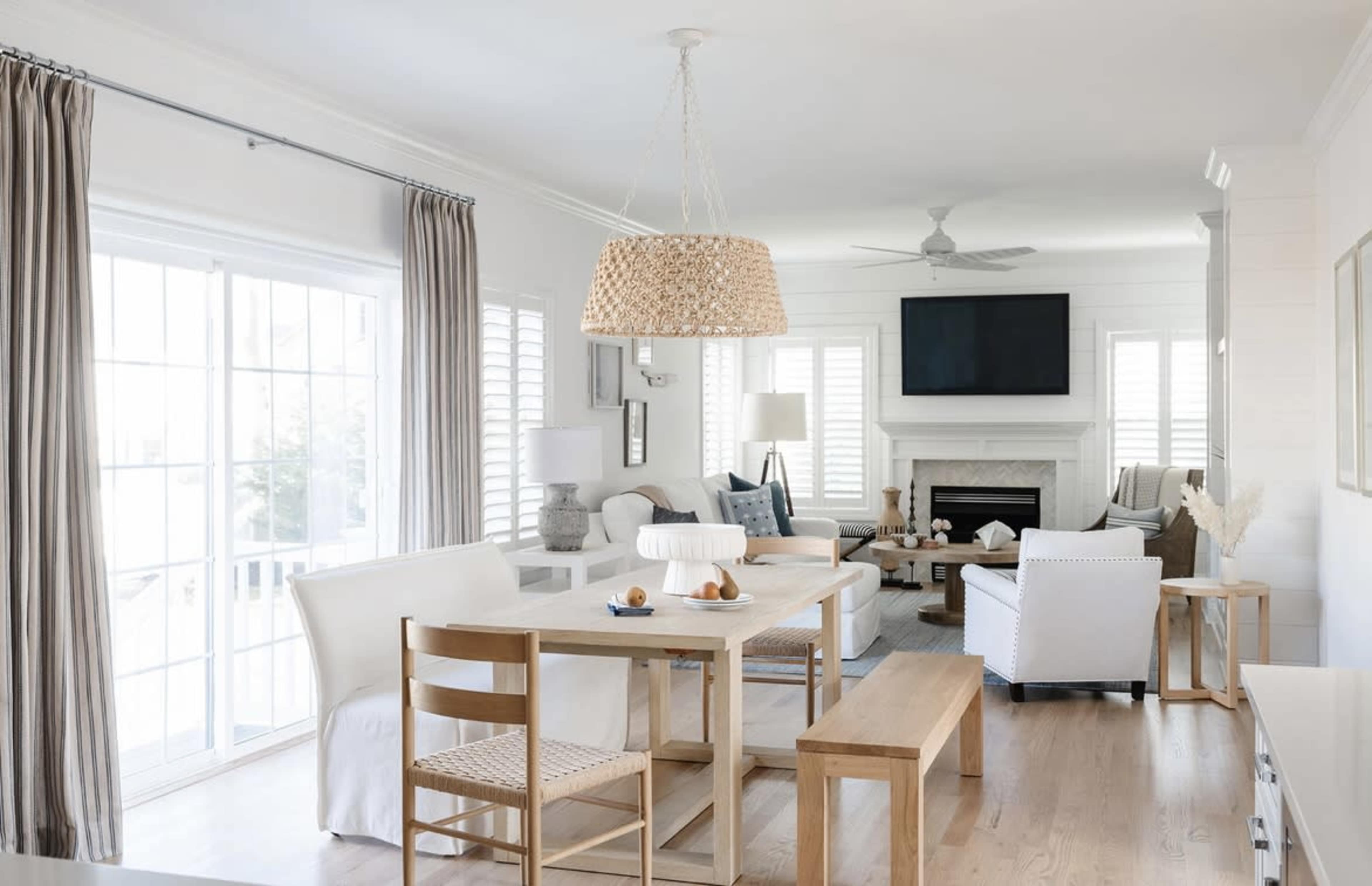 A modern living space featuring a dining area with a wooden table and chairs, a cozy seating area with a fireplace, and large windows allowing natural light to fill the room.