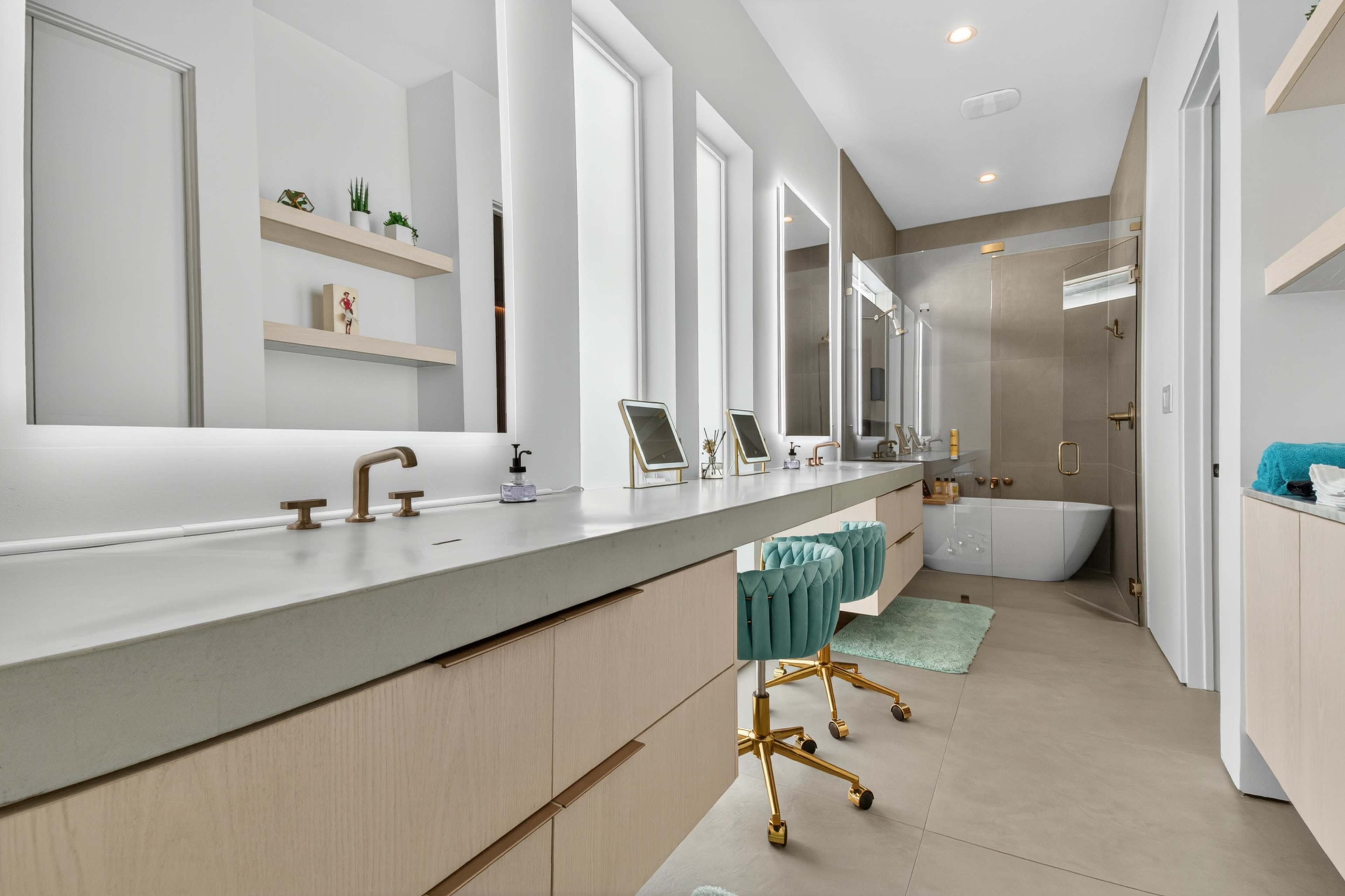 The image shows a modern bathroom with a long vanity, dual sinks, a large mirror, and a glass shower, complemented by light-colored cabinetry and stylish decor.