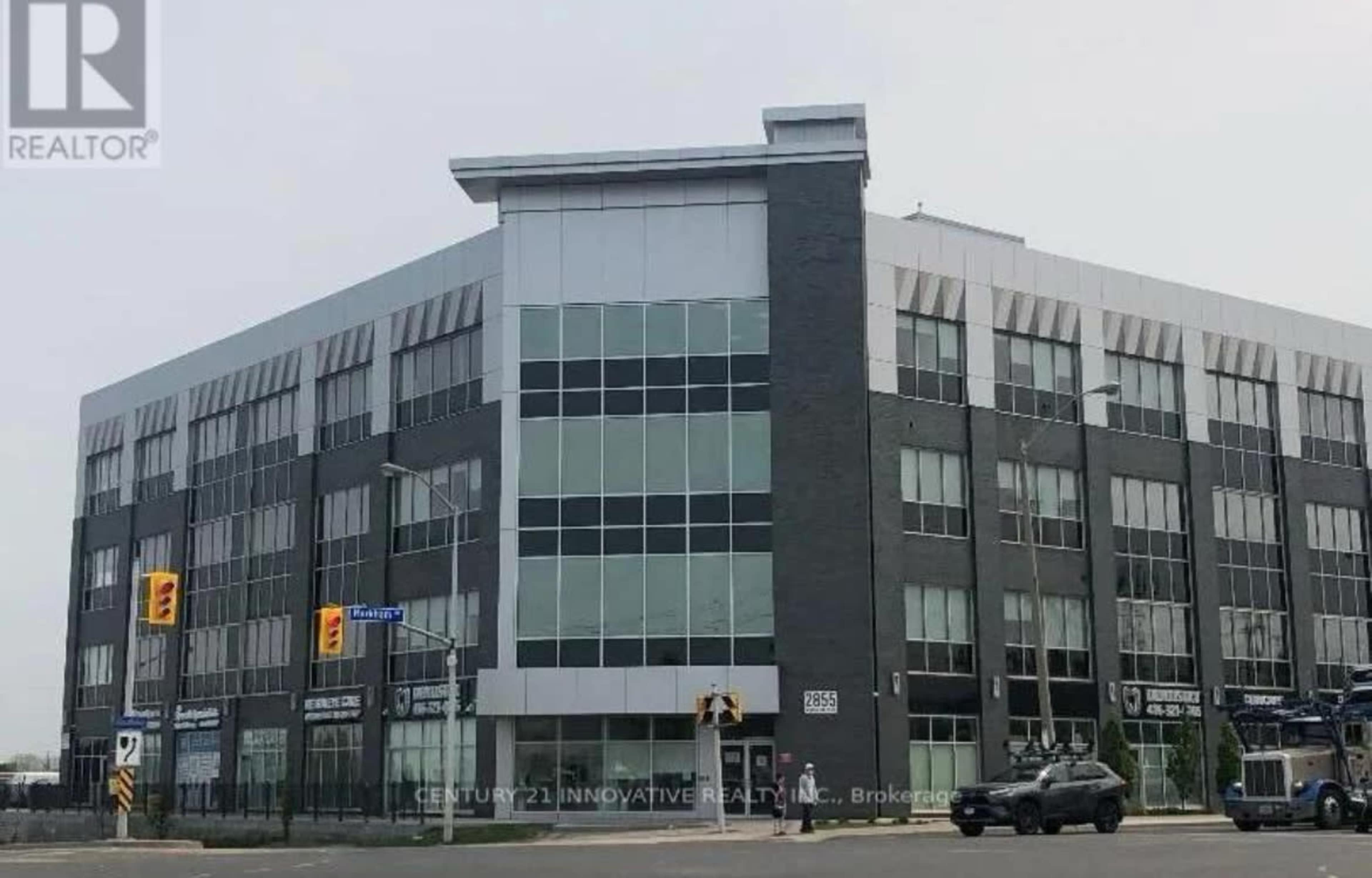 A modern multi-story commercial building located at the corner of a street with large glass windows and a prominent entrance.