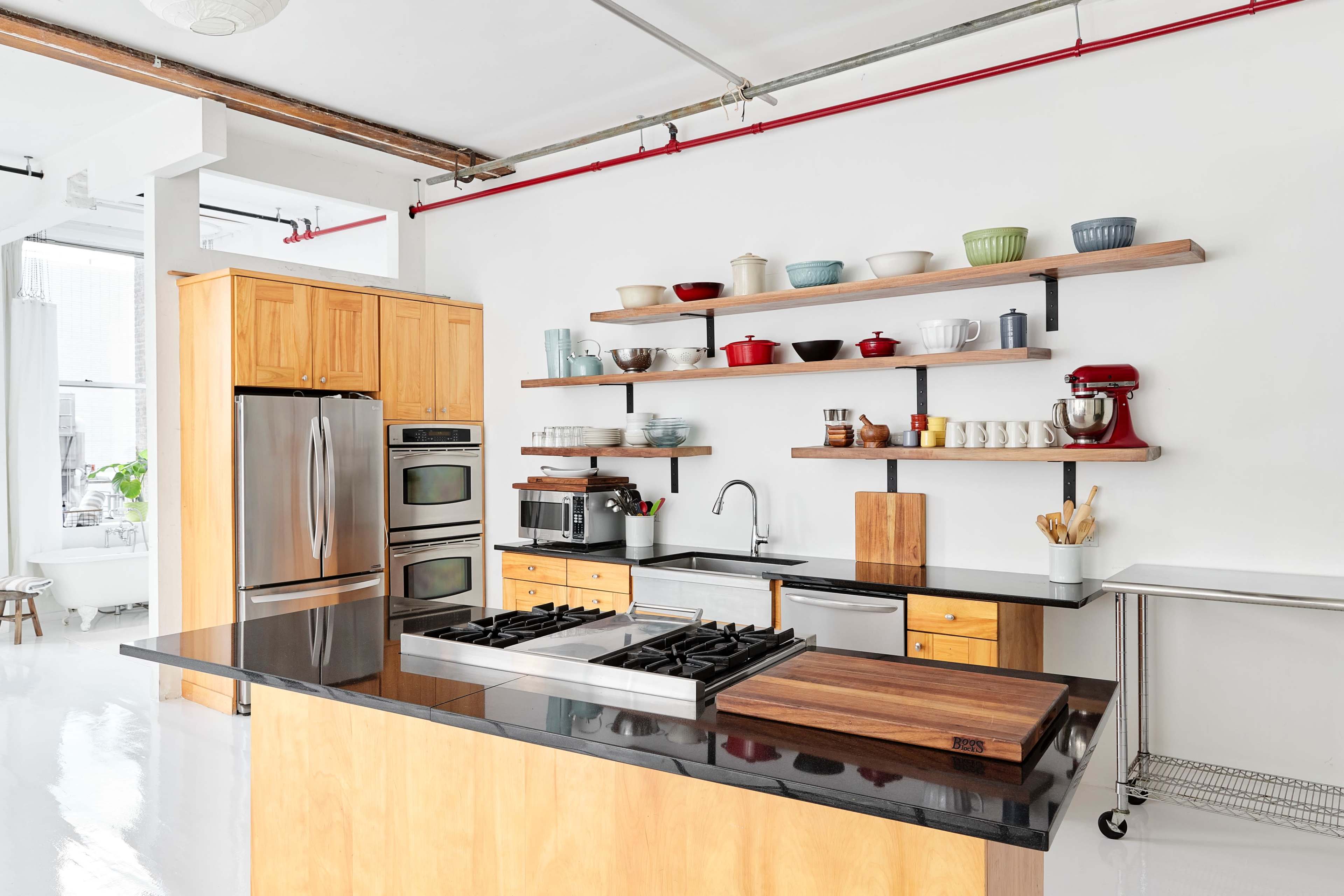 The kitchen features wooden cabinetry, stainless steel appliances, and open shelves displaying various dishes and cookware.