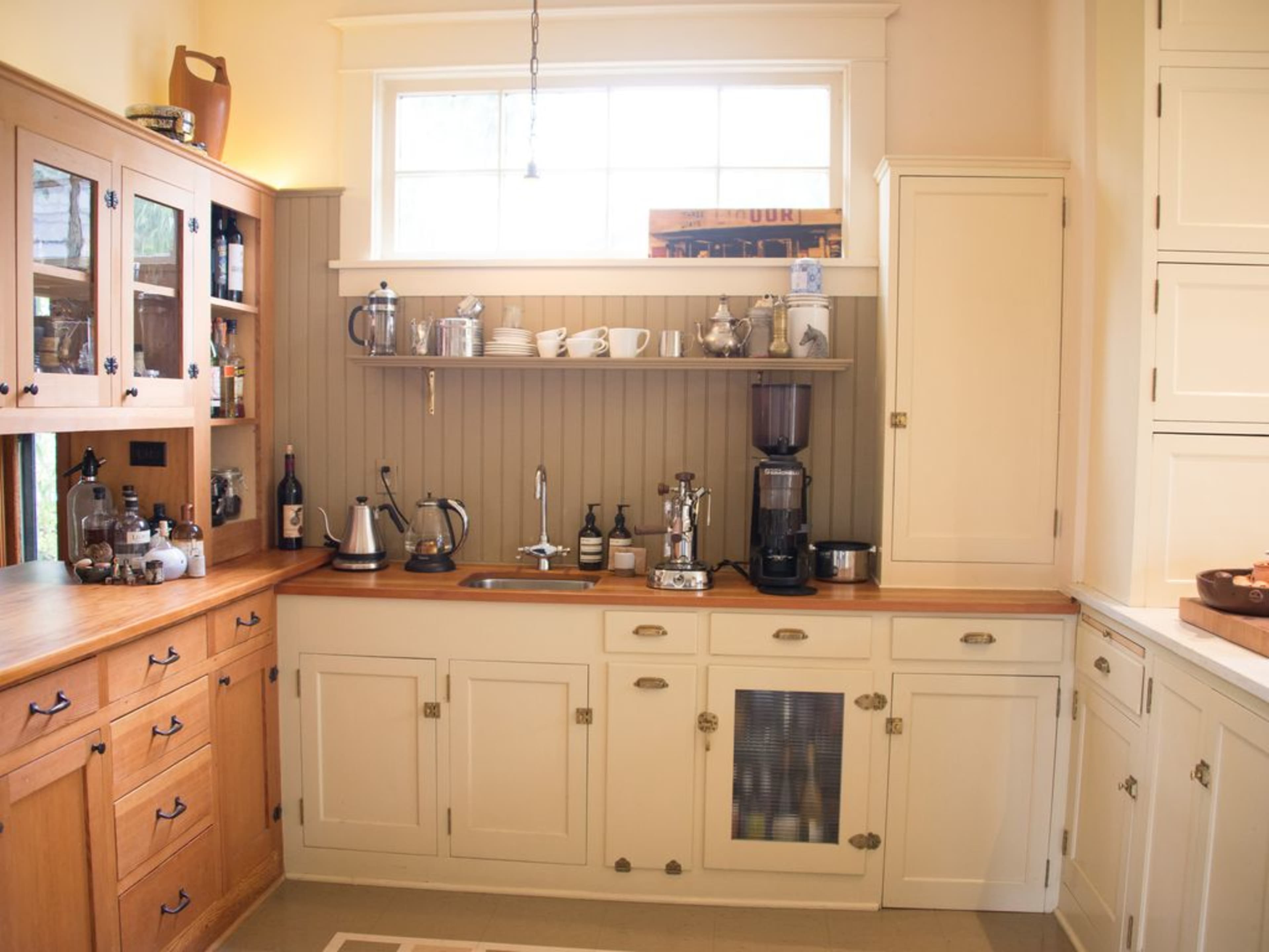 A kitchen featuring wooden cabinets, a countertop with various kitchen appliances, and a window above the sink.