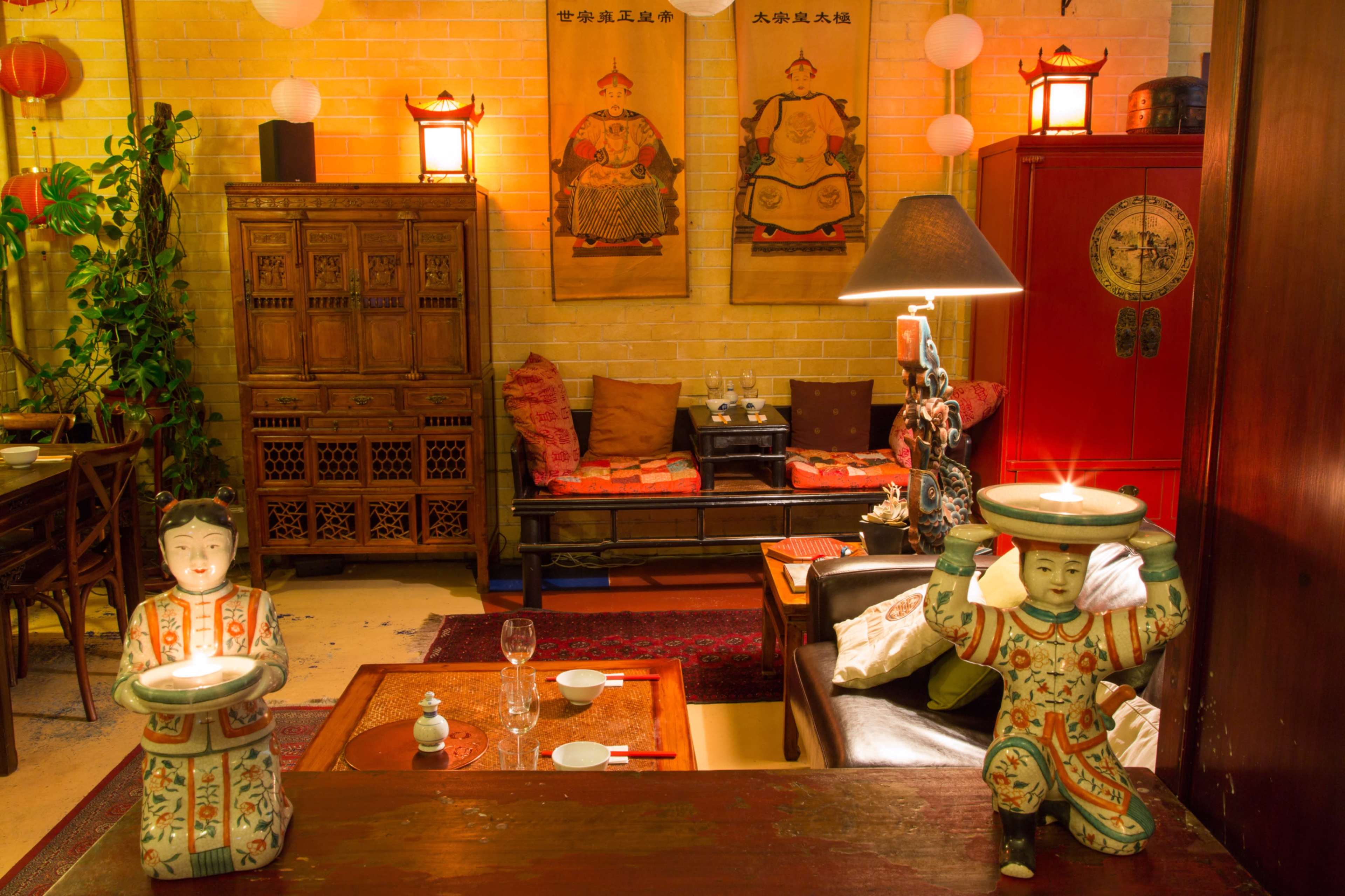 A cozy room decorated with traditional Asian furniture, sculptures, and soft lighting.