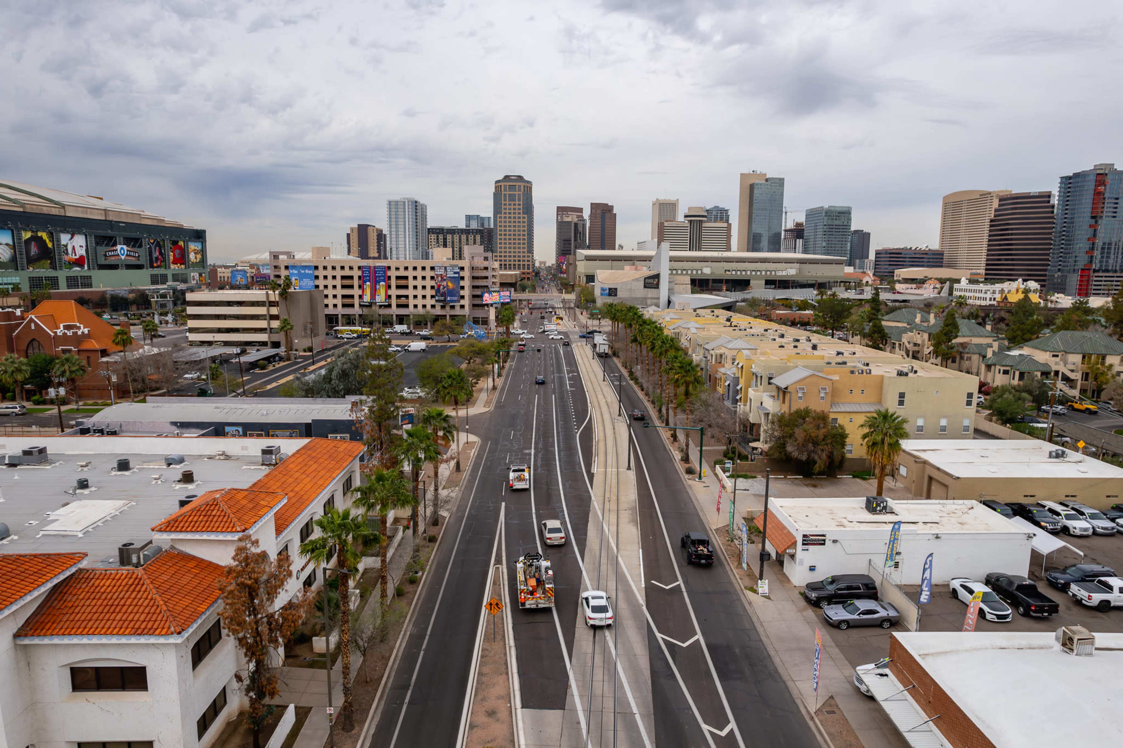 A view of a city skyline with buildings, a road featuring vehicles, and a mix of urban architecture, including warehouses and residential structures.