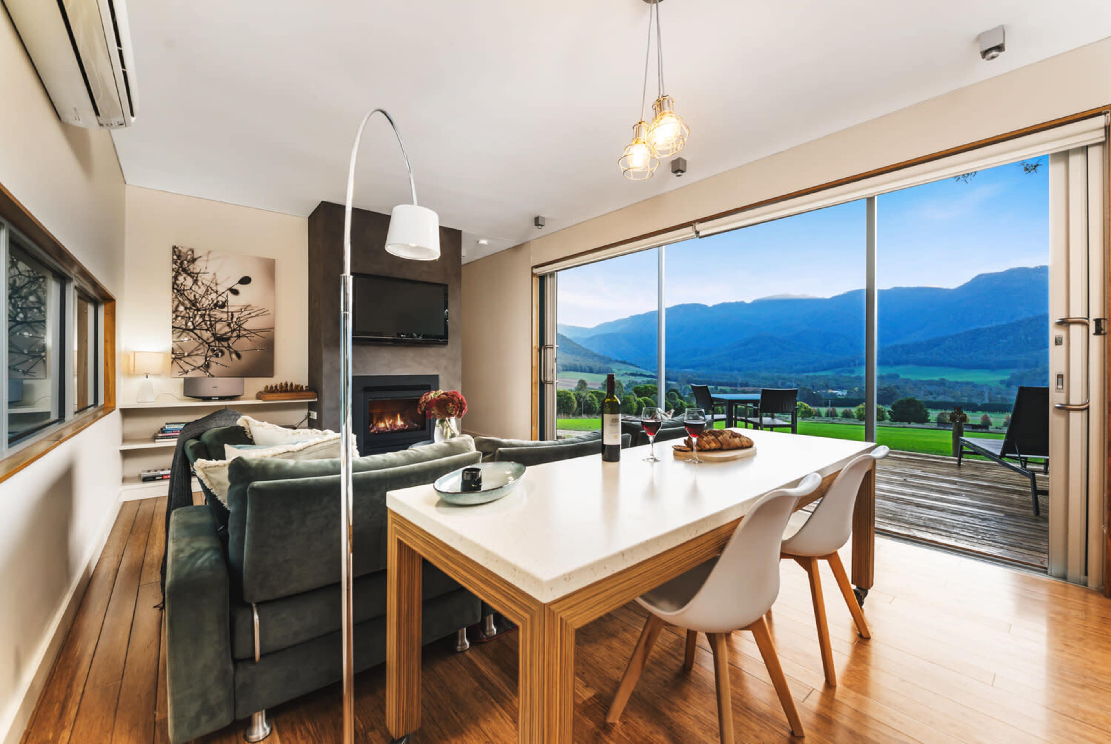 A modern living room and dining area with a large window overlooking a scenic mountain view.