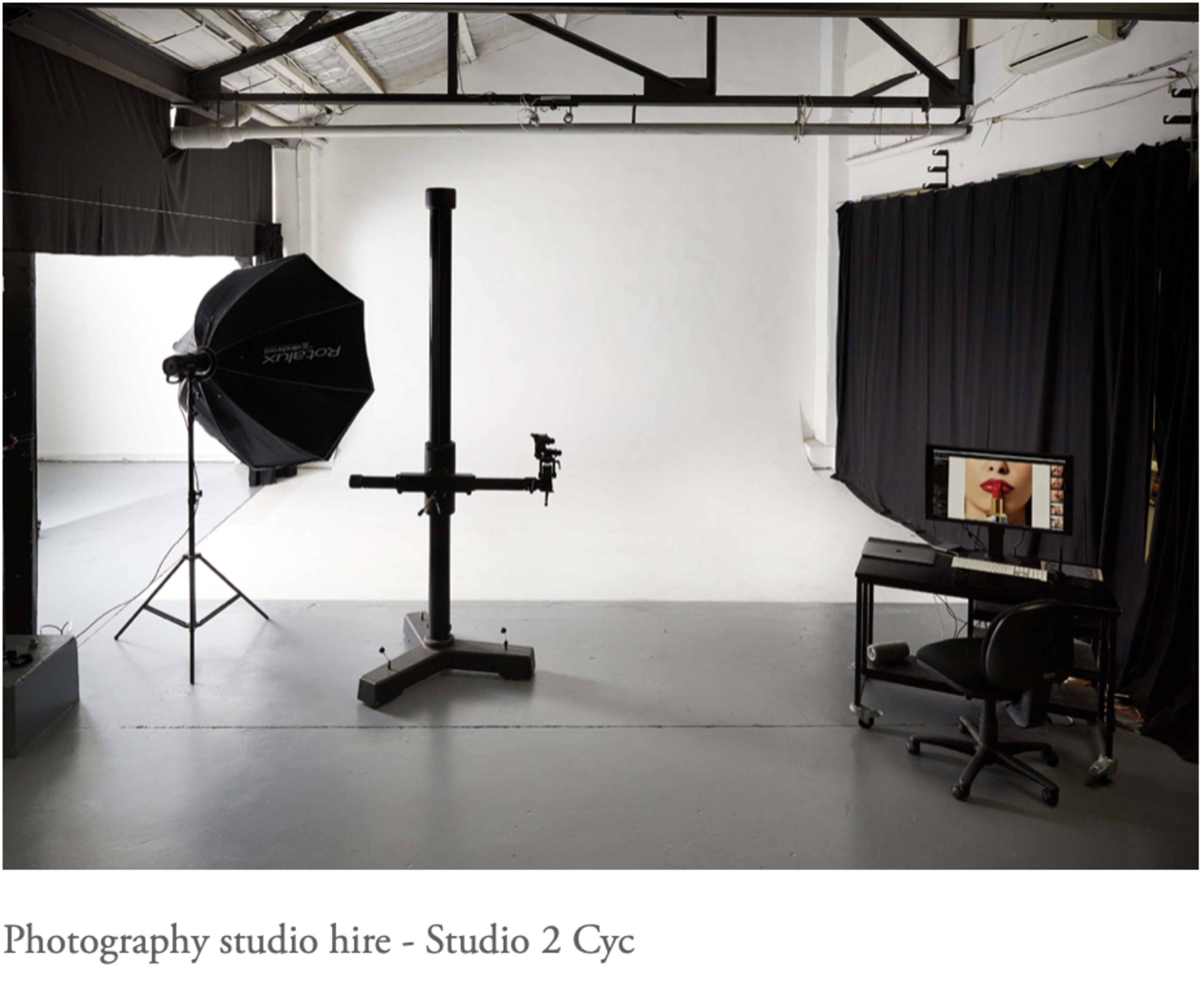 A photography studio equipped with a backdrop, lighting setup, and a computer workstation.