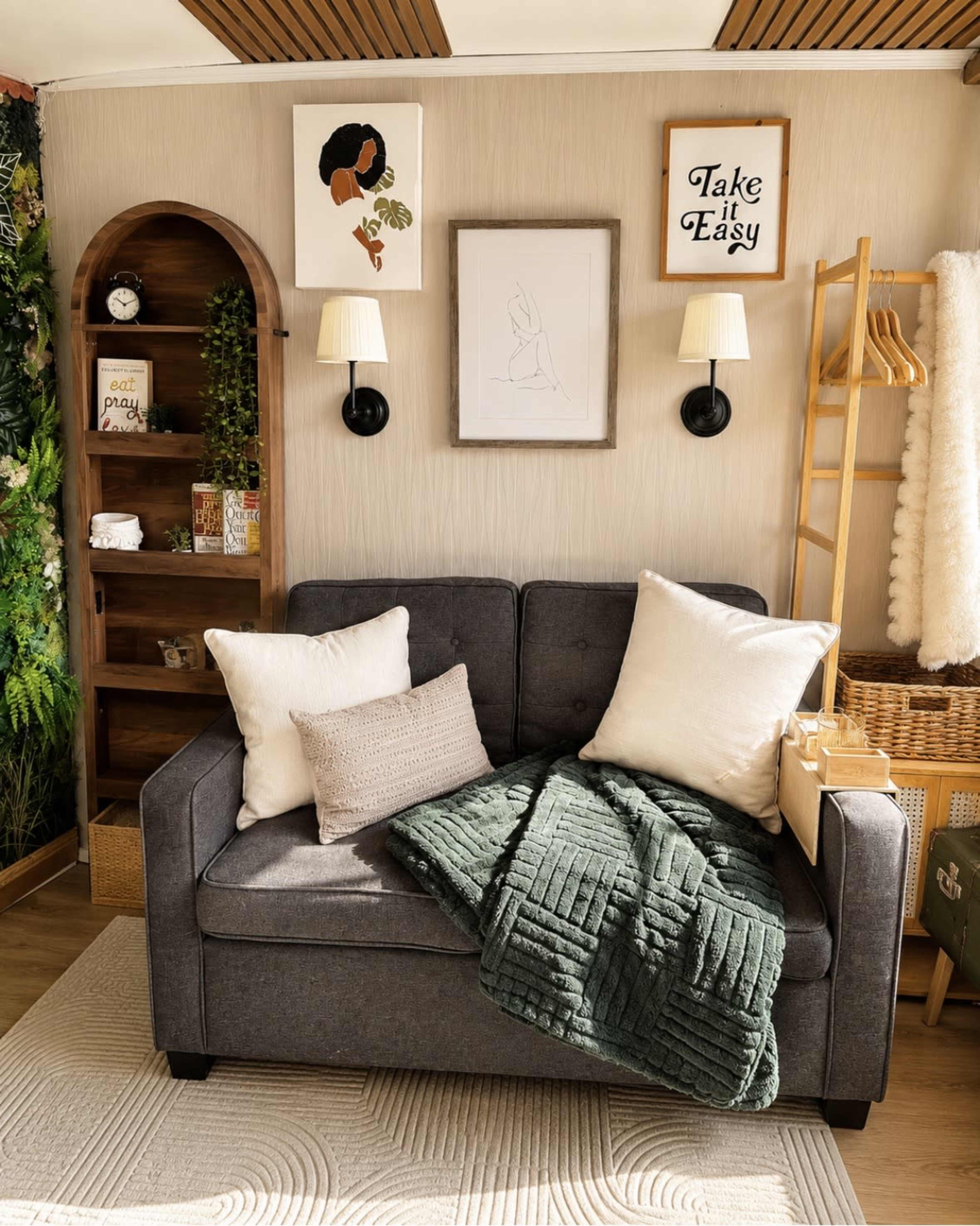 The image shows a cozy living space featuring a gray sofa adorned with decorative pillows and a green blanket, alongside a wooden bookshelf and wall art.