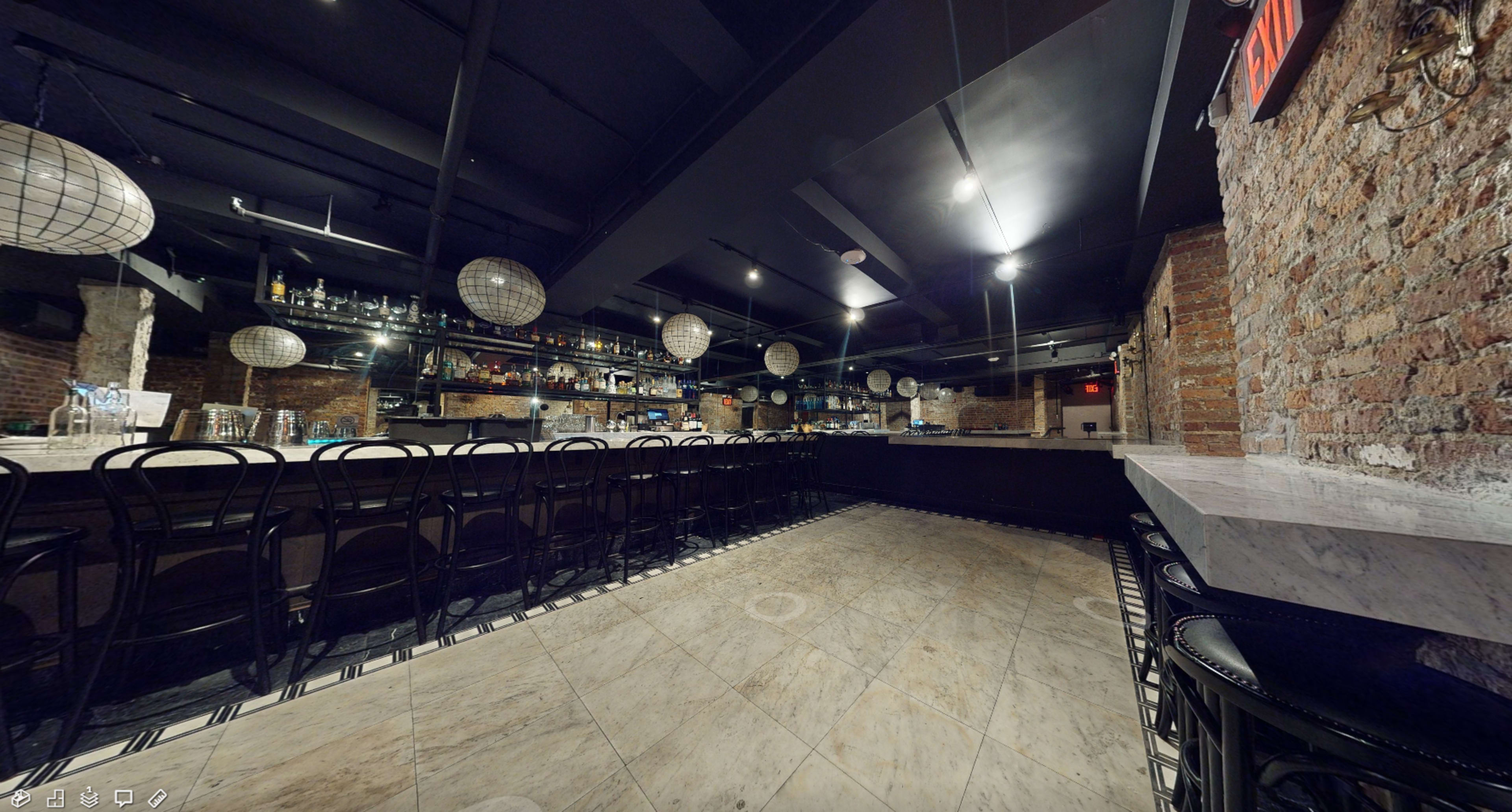 The image shows a modern bar interior with a long counter, circular pendant lights, and exposed brick walls.
