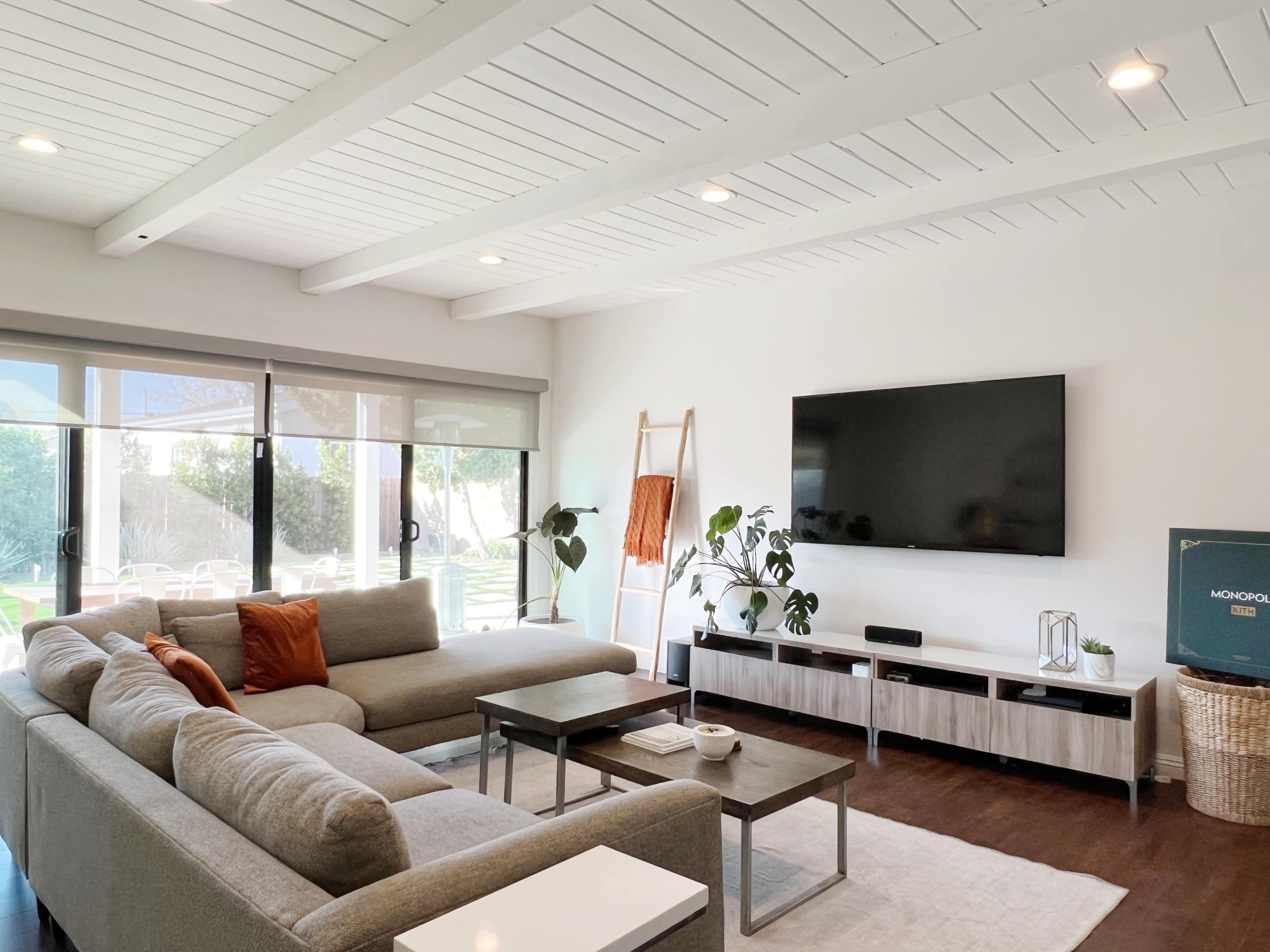 A modern living room featuring a large gray sectional sofa, a wall-mounted television, and a light-colored coffee table on a rug.