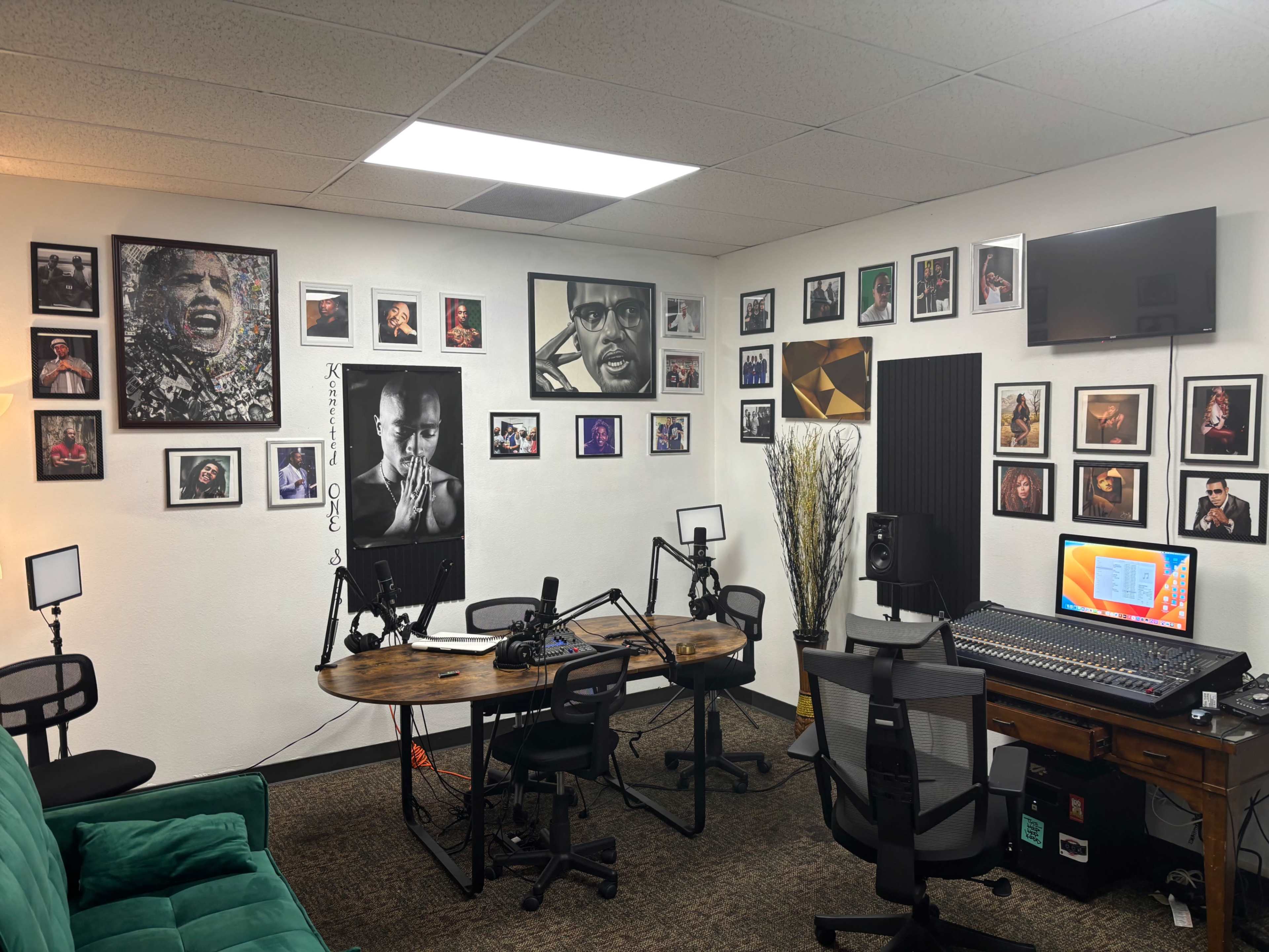 The image shows a recording studio with two desks, multiple microphones, a large mixing console, and various framed portraits of musicians on the walls.