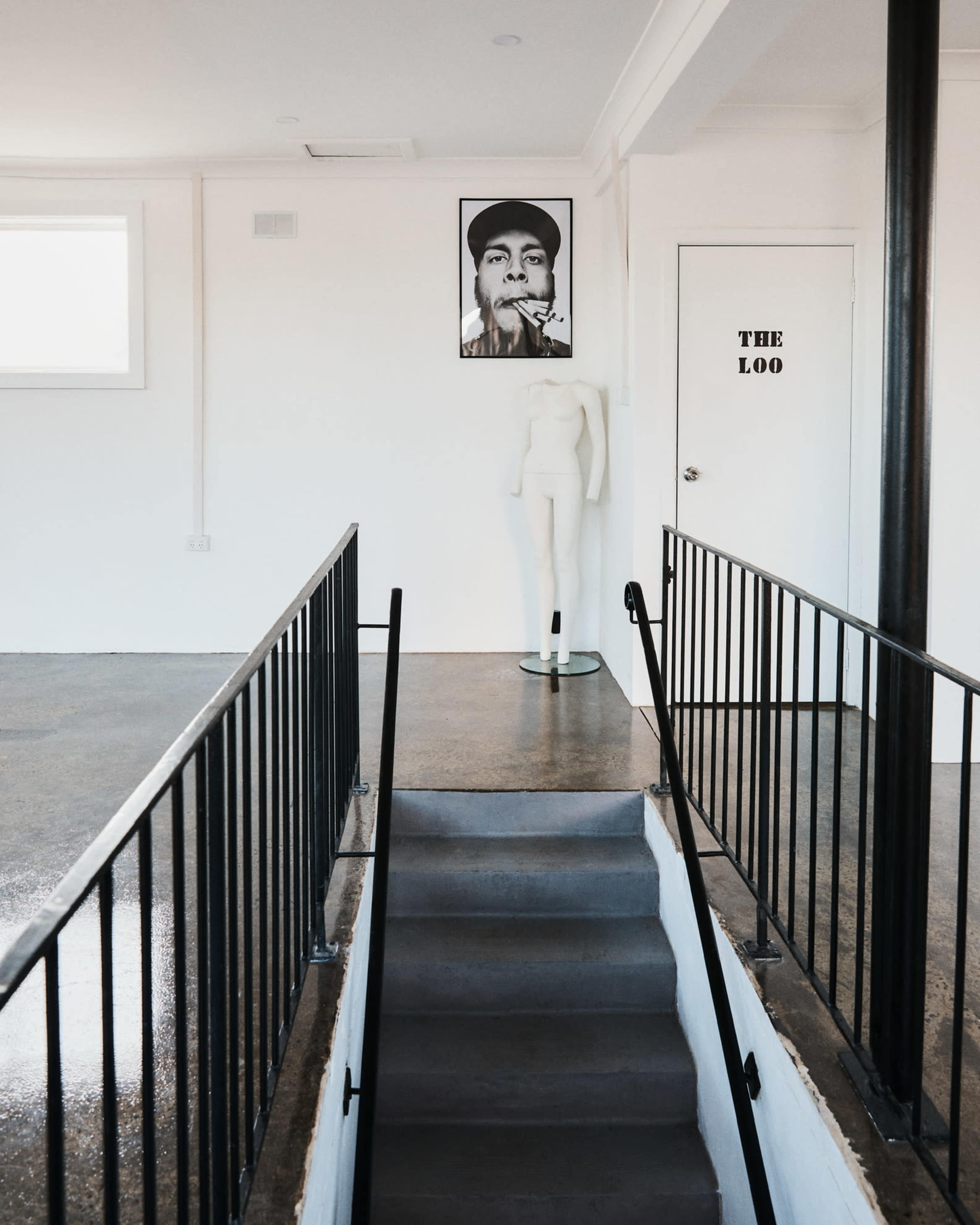 A staircase leading to a room with a large portrait on the wall and a mannequin positioned nearby, with a door labeled "THE LOO" visible.