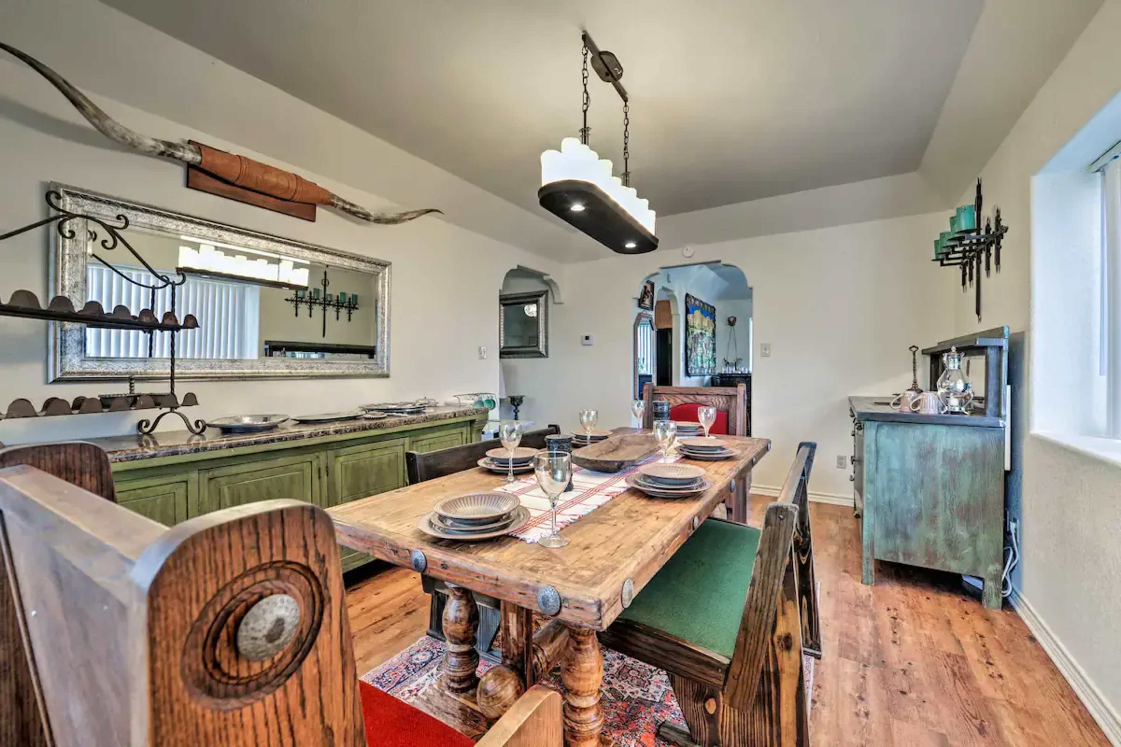 A dining room featuring a wooden table surrounded by chairs, a sideboard, and decorative wall art.