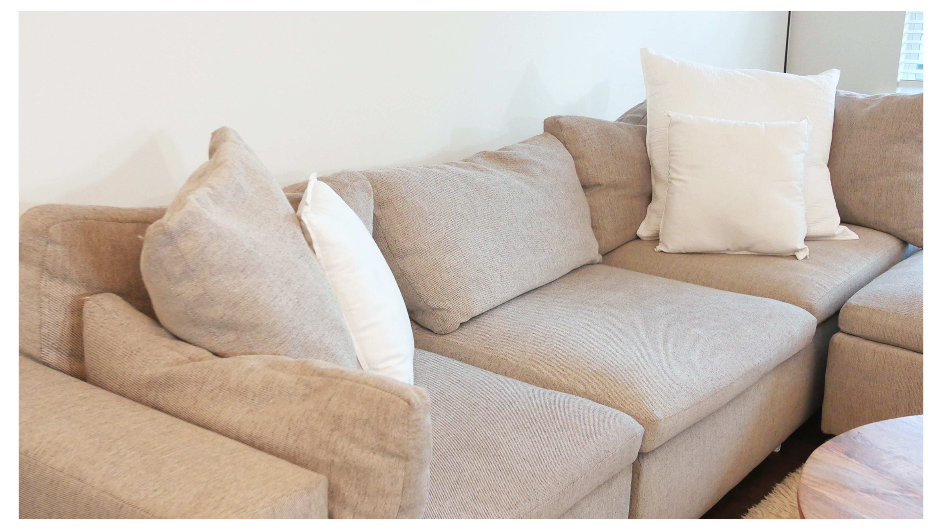 The image shows a light gray sectional sofa with multiple cushions arranged on it.
