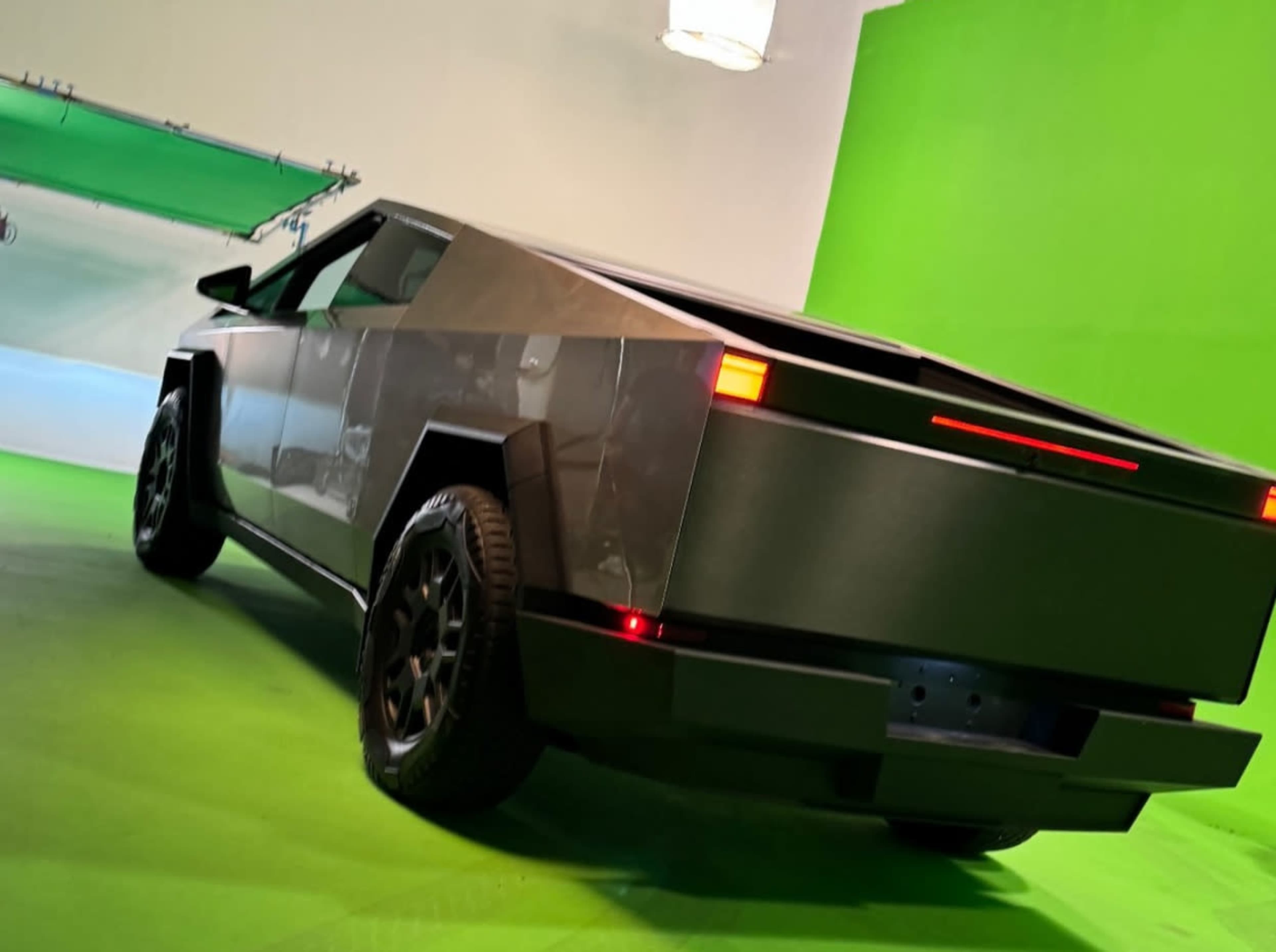 A futuristic electric truck is positioned in a studio with a green screen background.