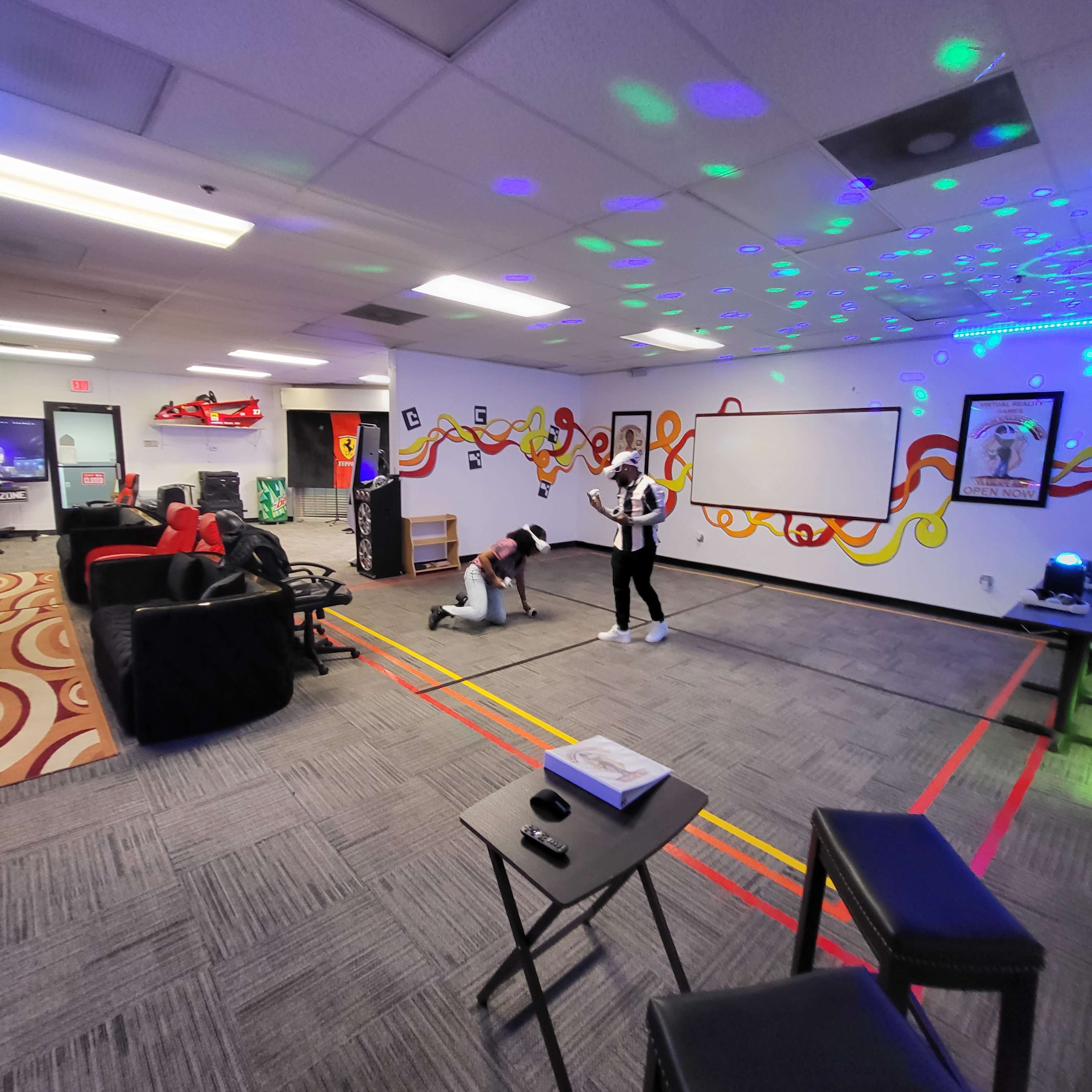 Two people are interacting in a colorful indoor recreational space with a patterned carpet and decorative walls.