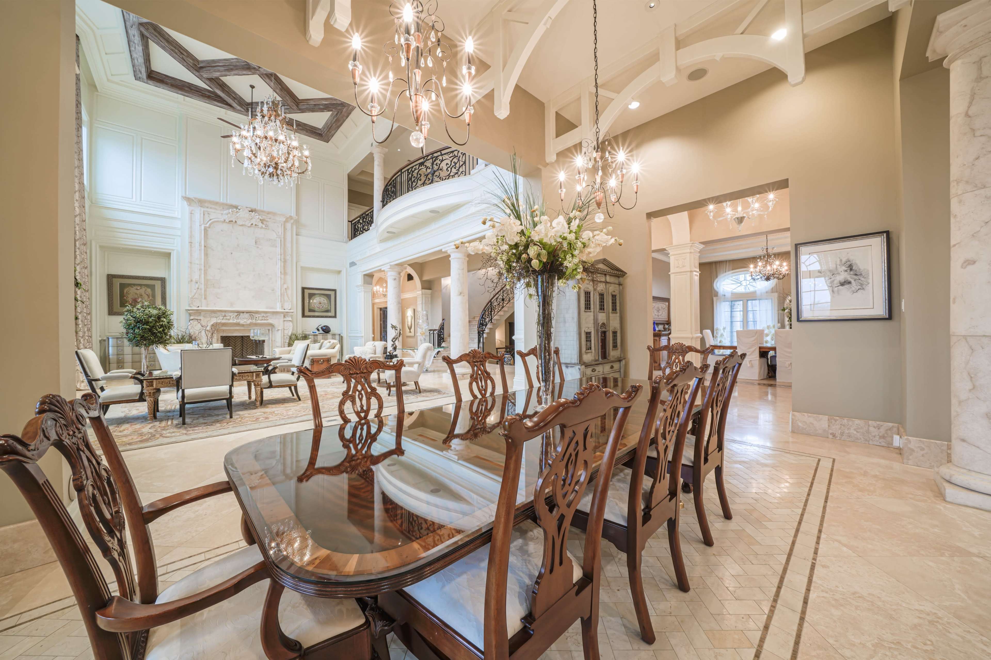 A spacious dining area featuring an elegant wooden table surrounded by chairs, with a view of a light-filled living space in the background.