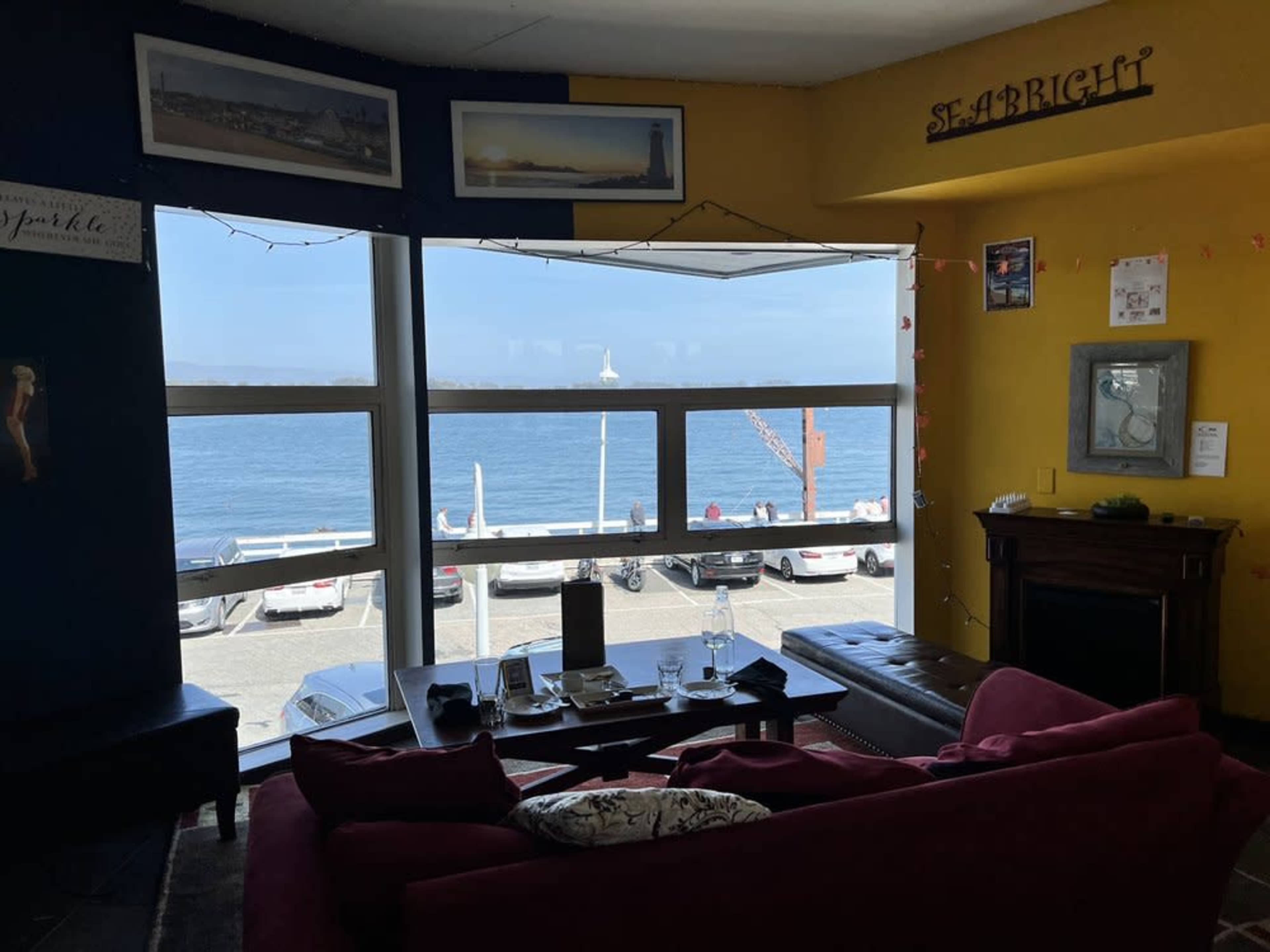 A cozy living room with a red sofa overlooks a seaside view featuring a marina and parked boats.