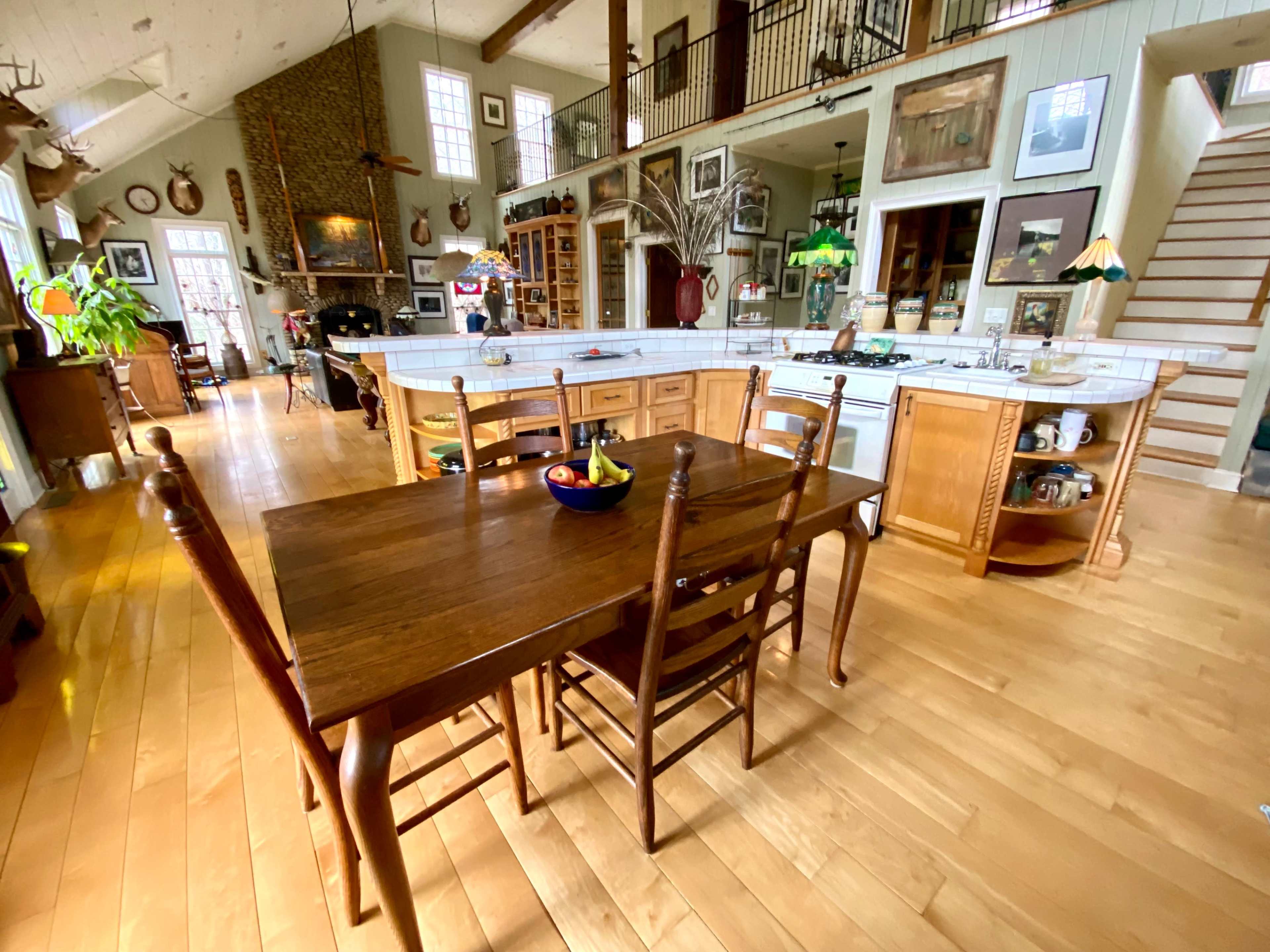 A spacious open-concept kitchen and dining area with a wooden table and chairs set in the foreground, surrounded by various decorative elements and appliances.