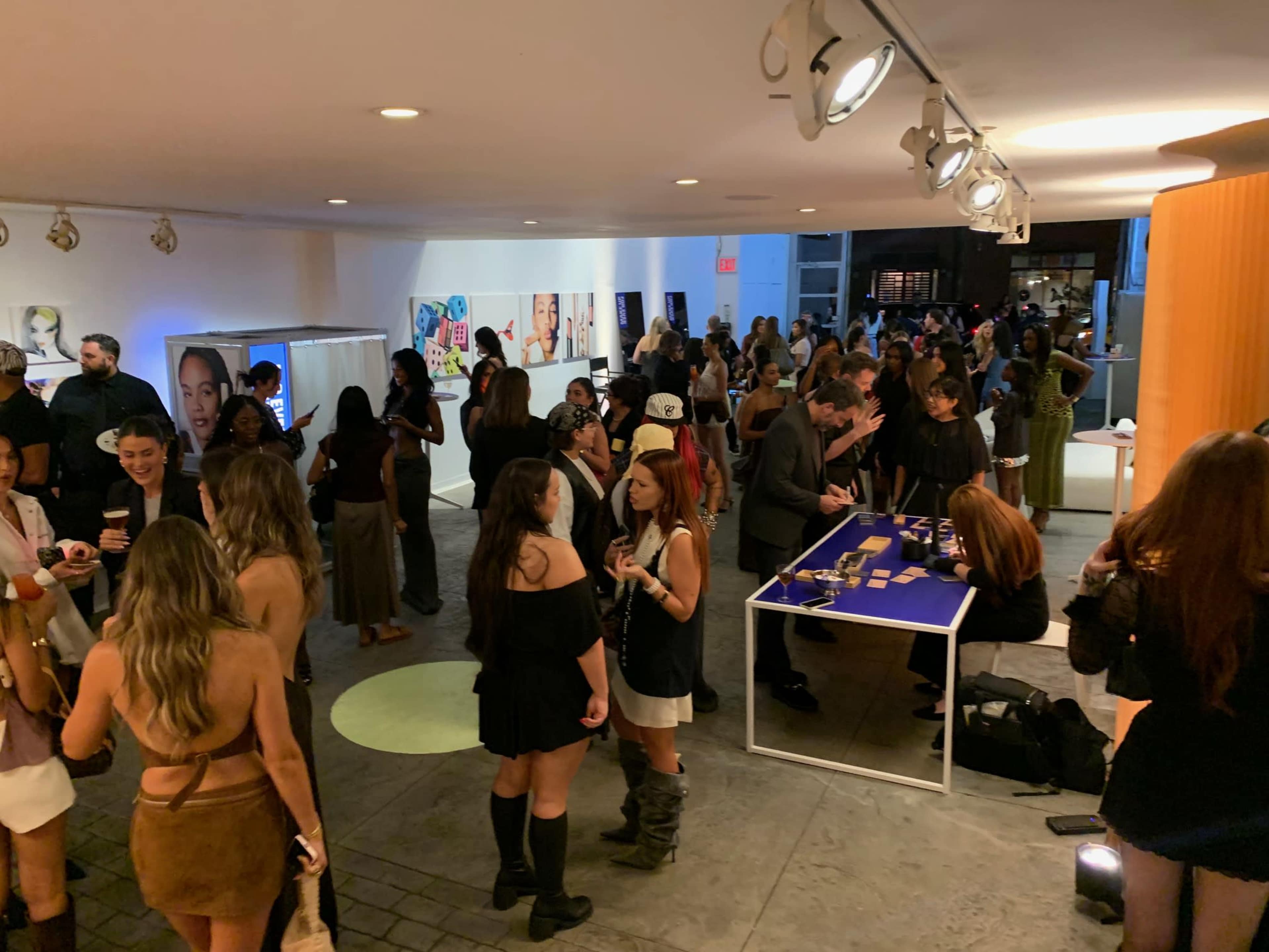 A crowded event space features guests mingling, socializing, and engaging in various activities amidst modern decor.
