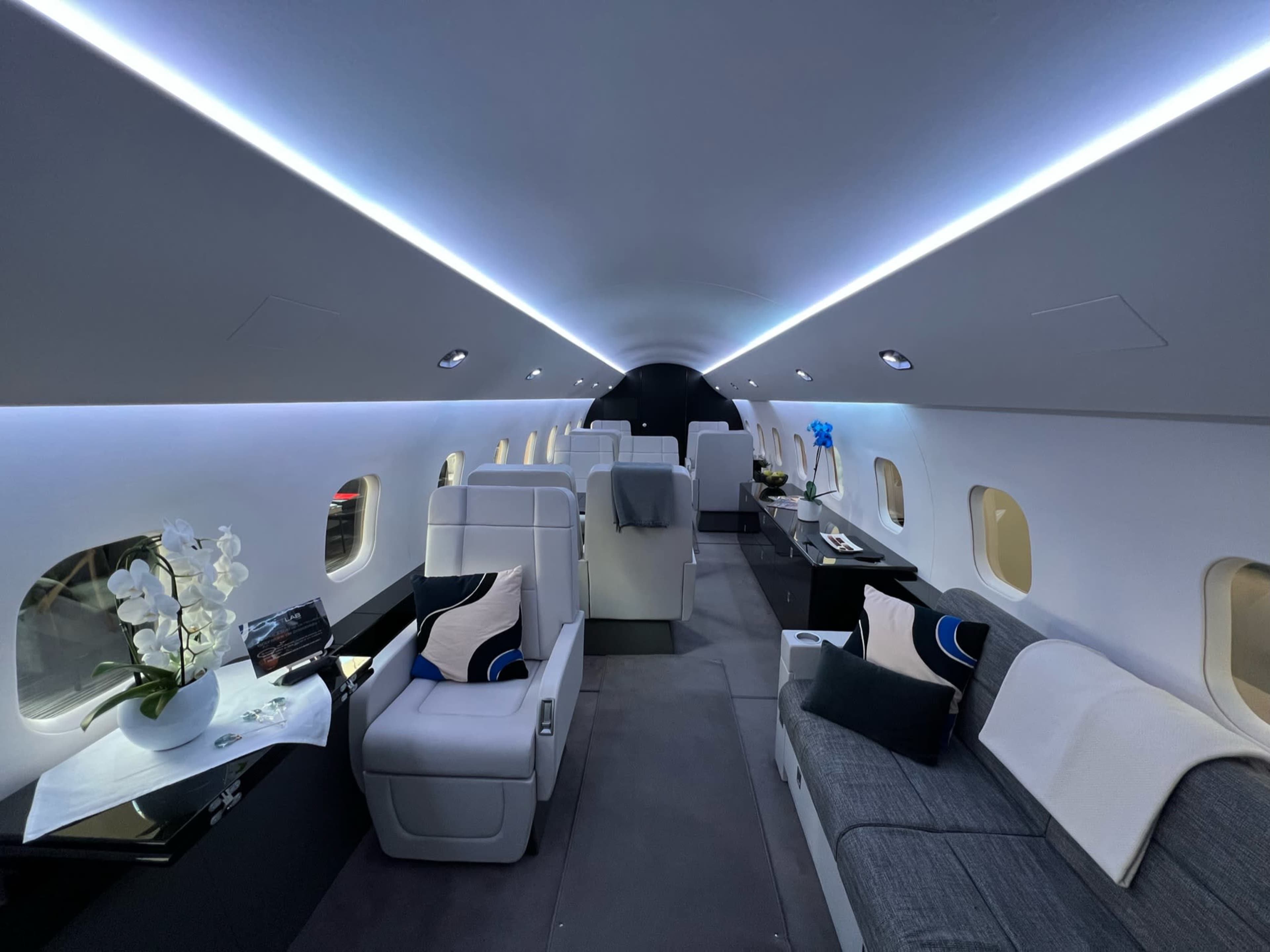 The interior of a private jet features spacious seating, modern decor, and ambient lighting.