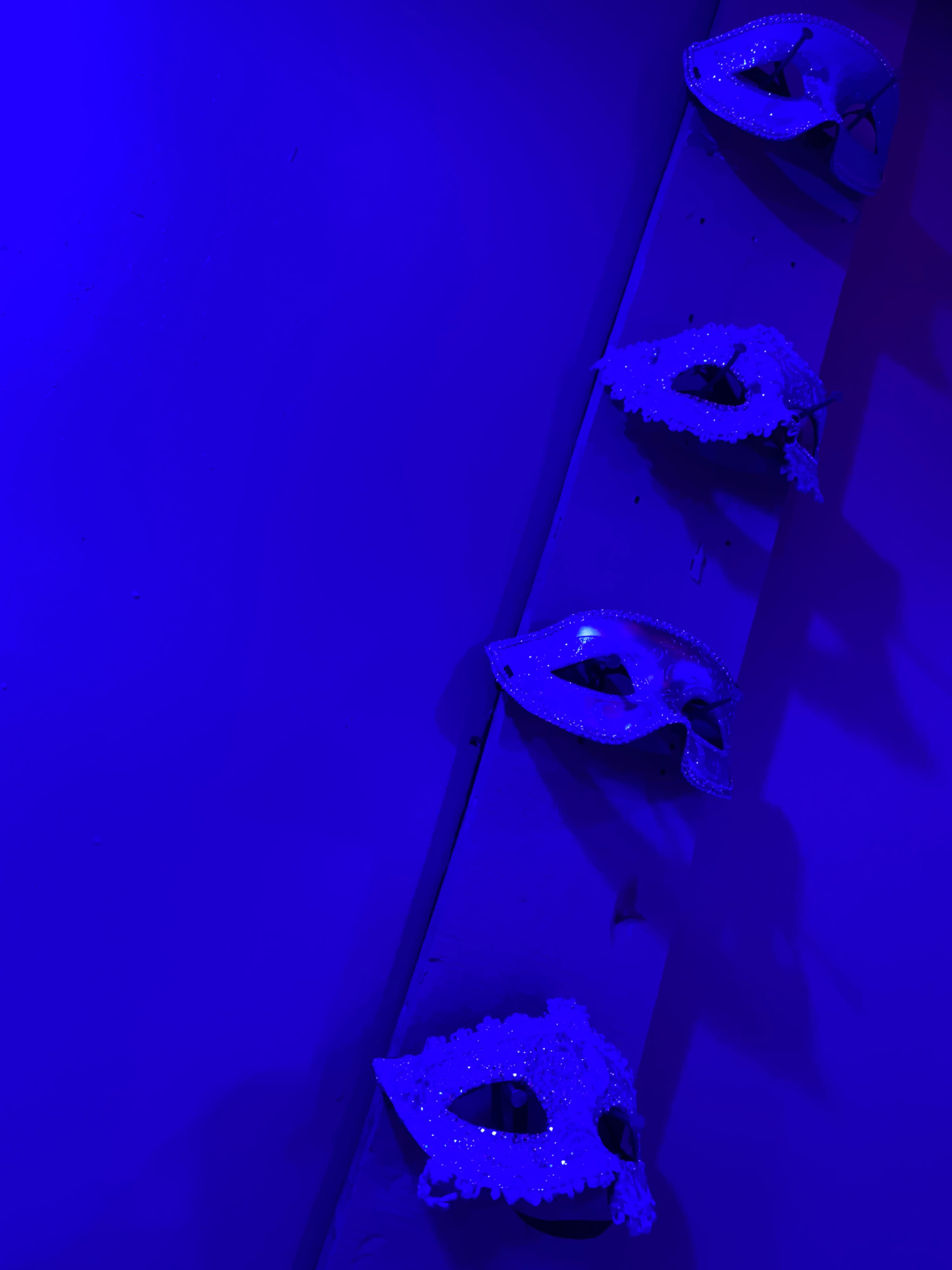 Four decorative masks hang on a blue-lit wall.