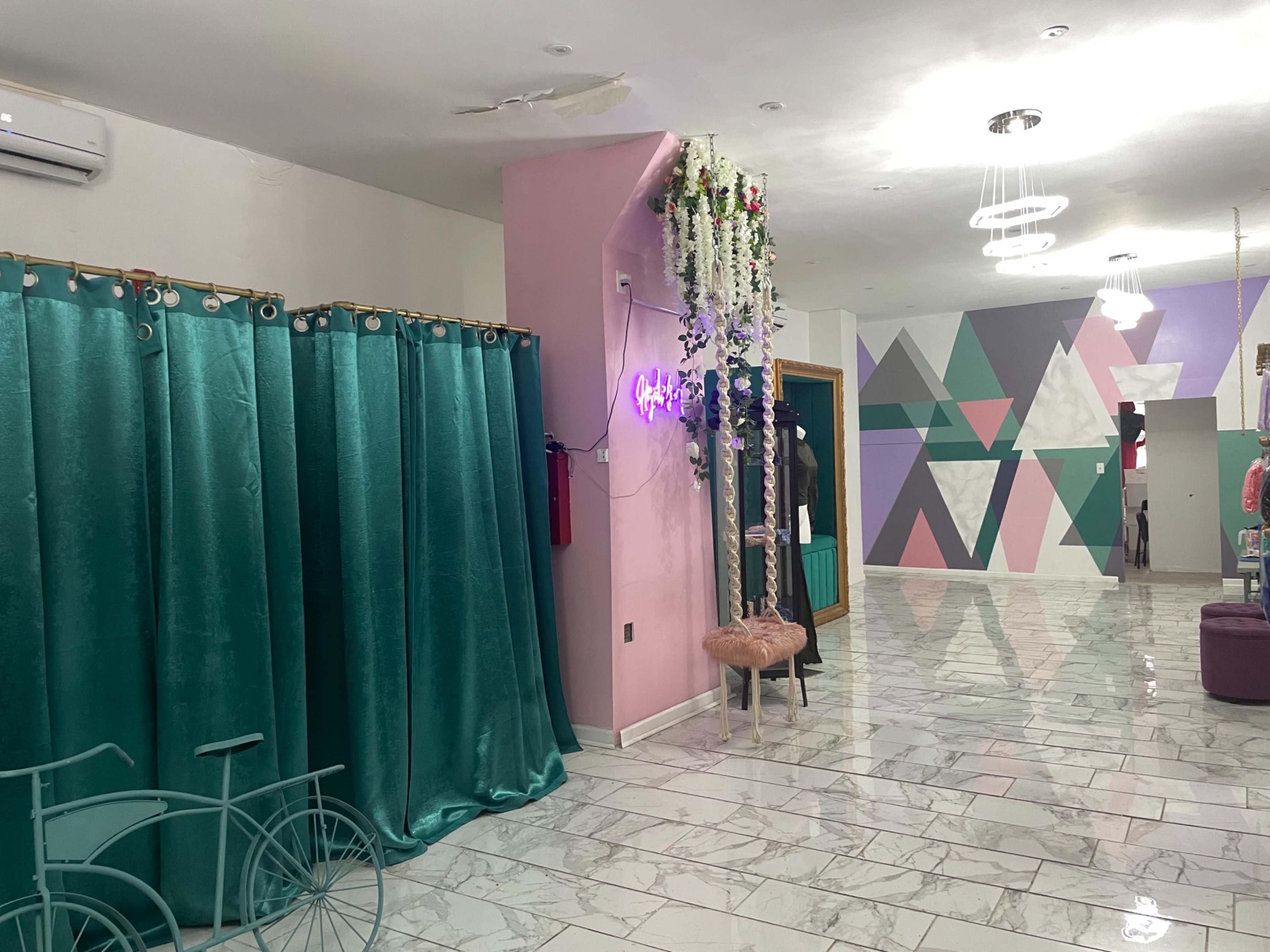 A spacious interior with teal curtains, minimalist decor, and geometric wall designs.
