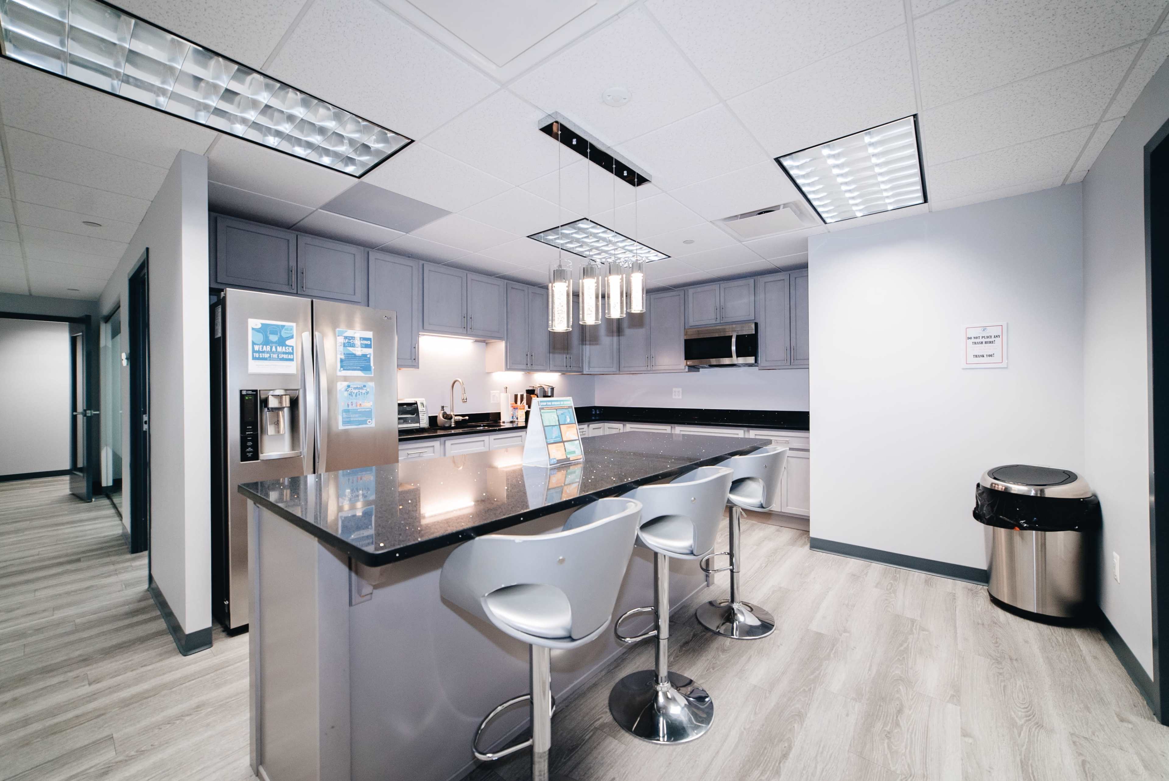 The kitchen features modern gray cabinetry, a large island with seating, and stainless steel appliances.