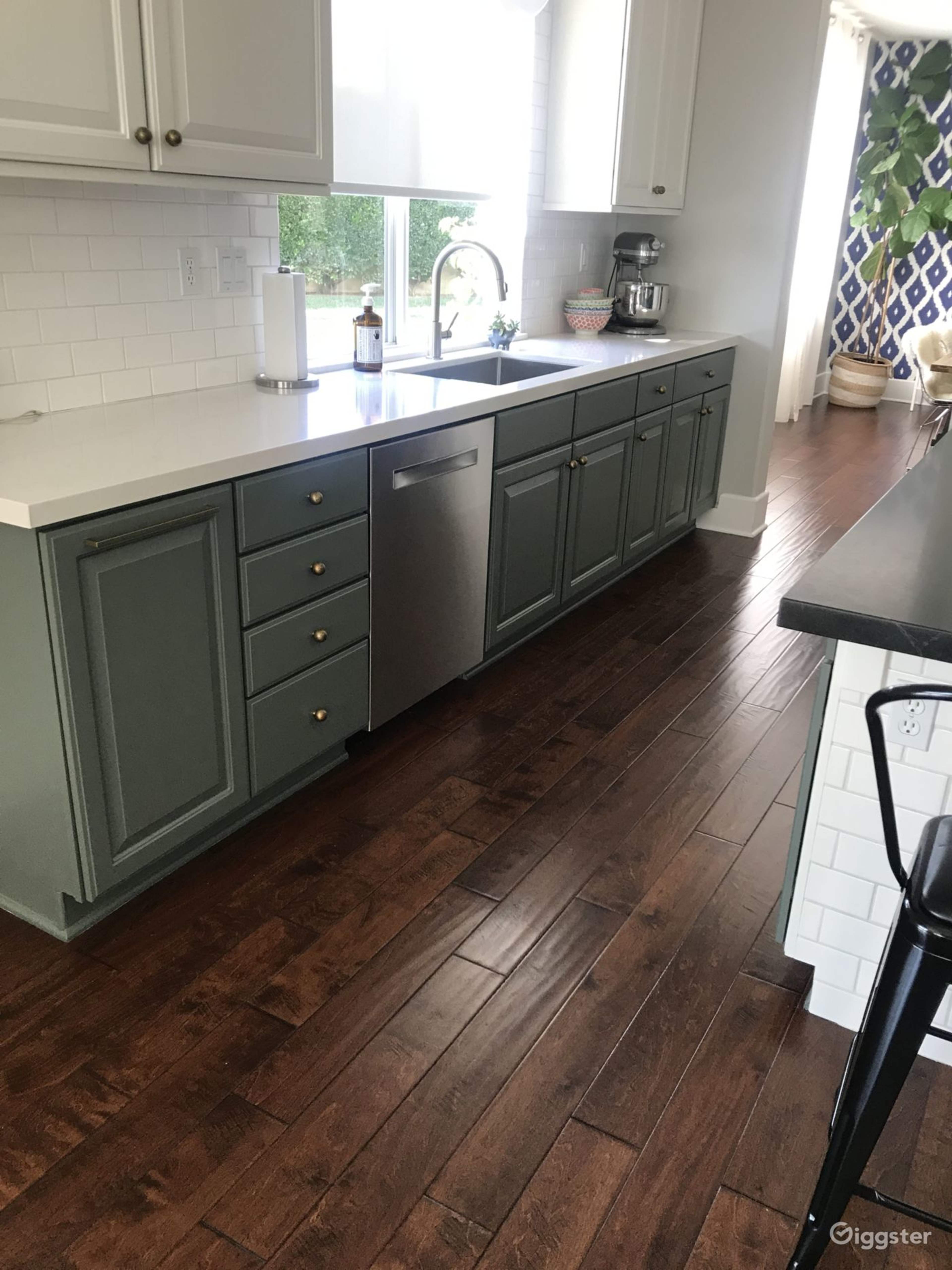A modern kitchen with gray cabinets, a stainless steel dishwasher, and dark wood flooring.