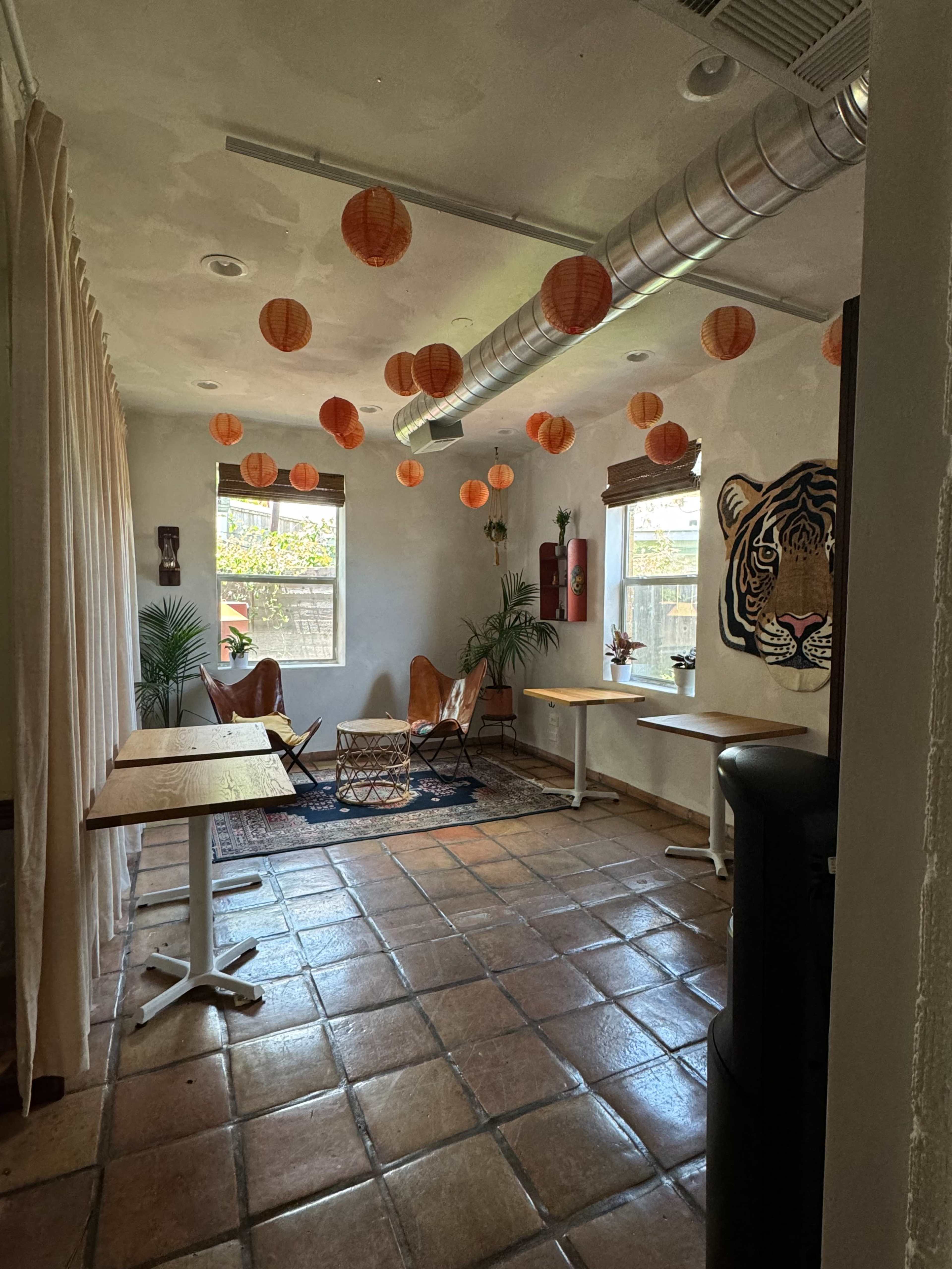 The room features two brown chairs, a patterned rug, a water cooler, and orange paper lanterns hanging from the ceiling.