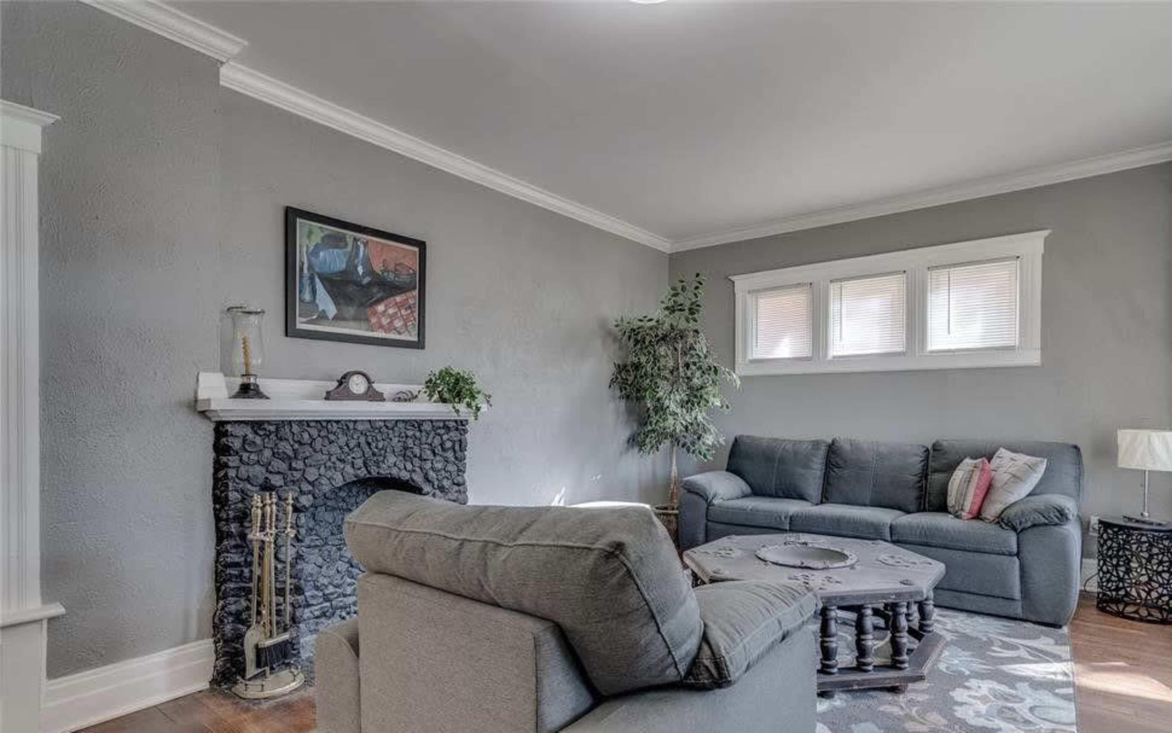 The living room features gray walls, a dark stone fireplace, two sofas, a coffee table, and a small lamp.